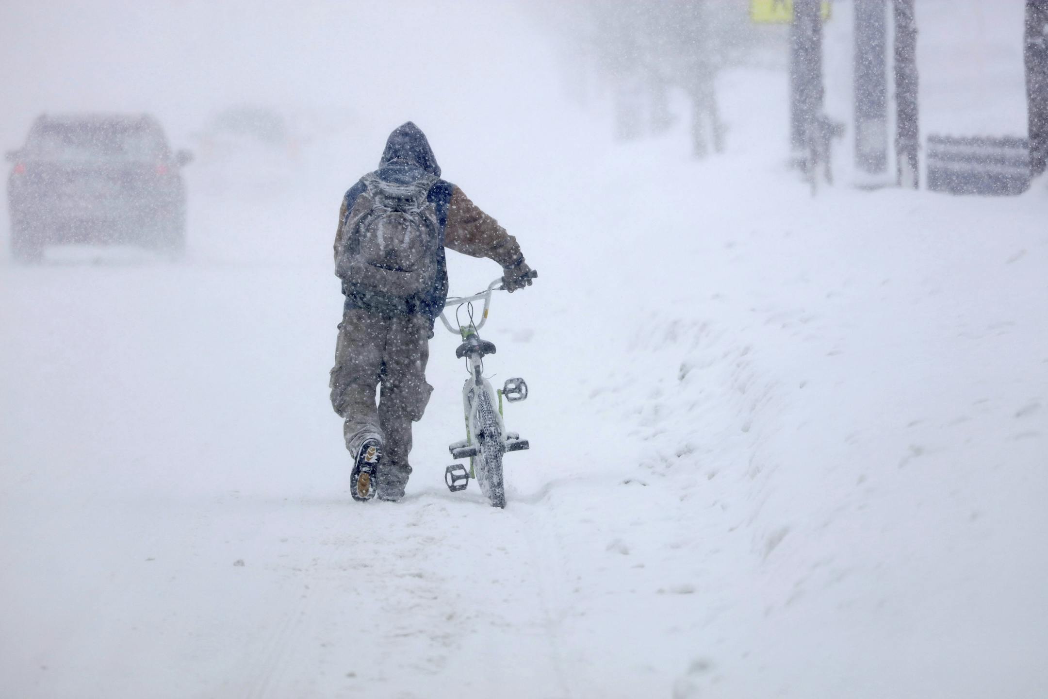 Austin Tauber heads home with his bicycle Wednesday morning, Feb. 20, 2019, in the snow in Anoka, Minn. Forecasters are warning residents in parts of Minnesota and western Wisconsin the advancing winter storm could produce up to 9 inches of snow.