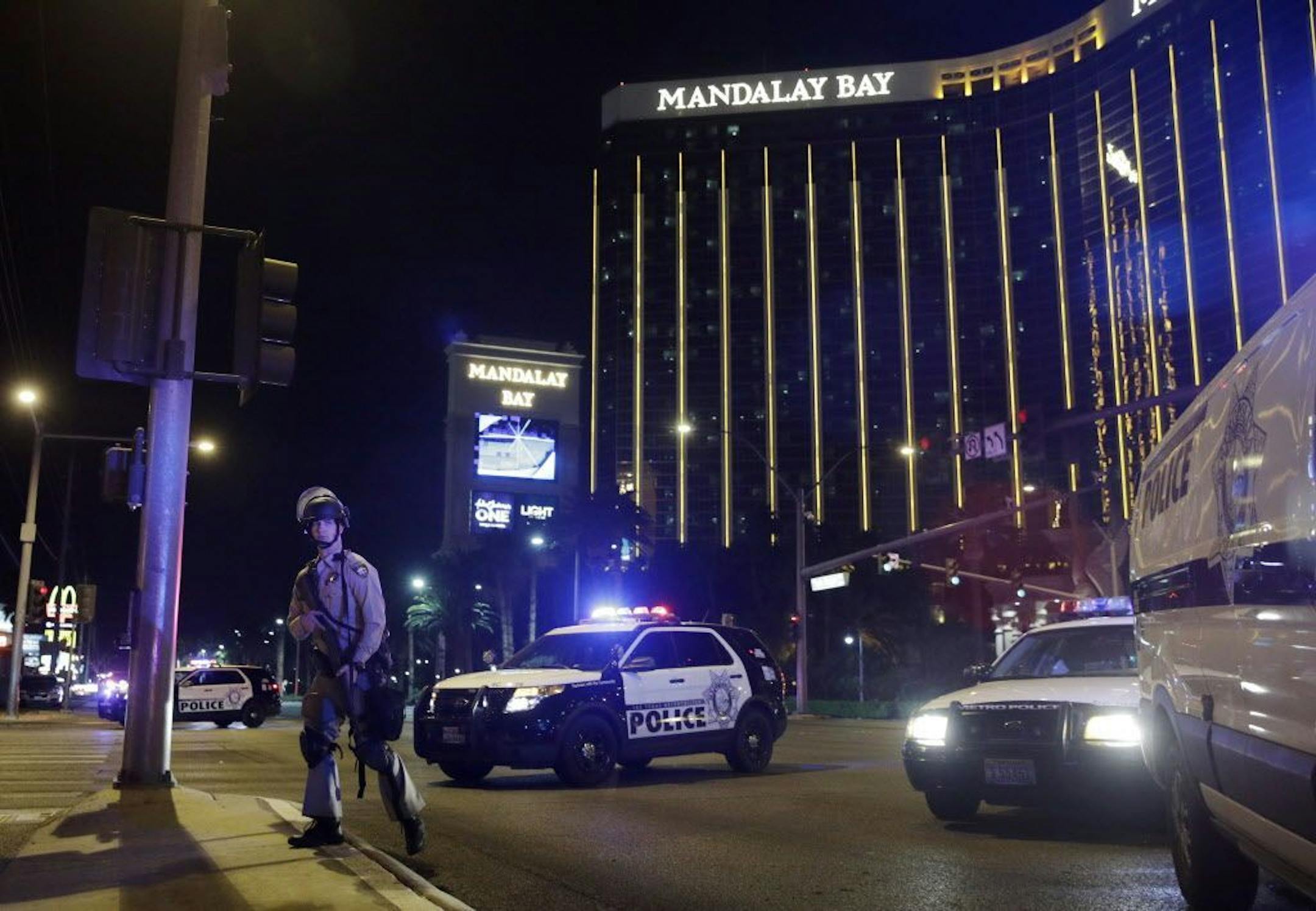 FILE - In this Sunday, Oct. 1, 2017 file photo, police officers stand along the Las Vegas Strip near the Mandalay Bay resort and casino during a shooting at a country music festival, in Las Vegas. Police initially said Stephen Paddock stopped firing on the music festival concert crowd below to shoot through his door and wound a Mandalay Bay security guard who was outside. On Monday, Oct. 9, 2017, they said the guard actually was wounded before Paddock started the massacre.
