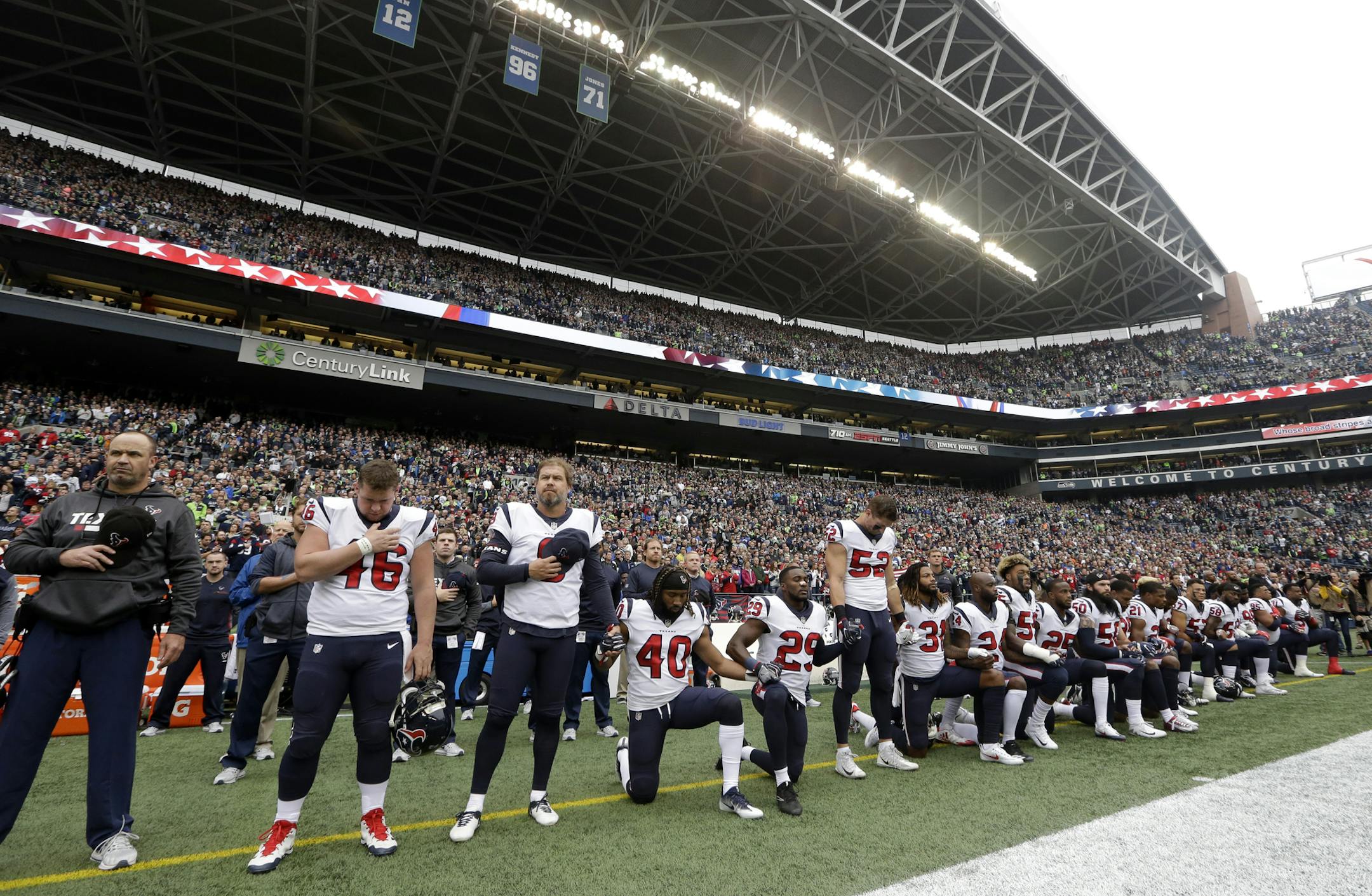 Houston Texans players kneel and stand during the singing of the national anthem before an NFL football game against the Seattle Seahawks, Sunday, Oct. 29, 2017, in Seattle. (AP Photo/Elaine Thompson)