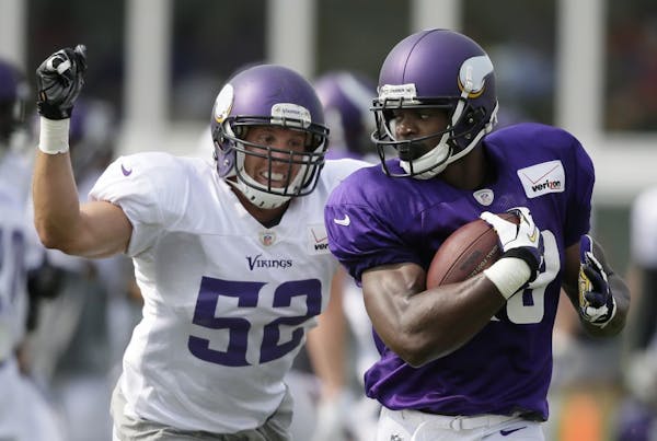 Minnesota Vikings running back Adrian Peterson, right, runs from outside linebacker Chad Greenway during training camp in 2014.