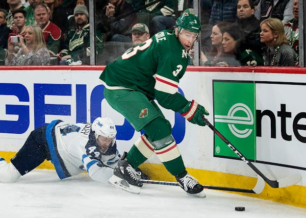 Josh Morrissey (44) and Charlie Coyle (3) fought for the puck in the first period.