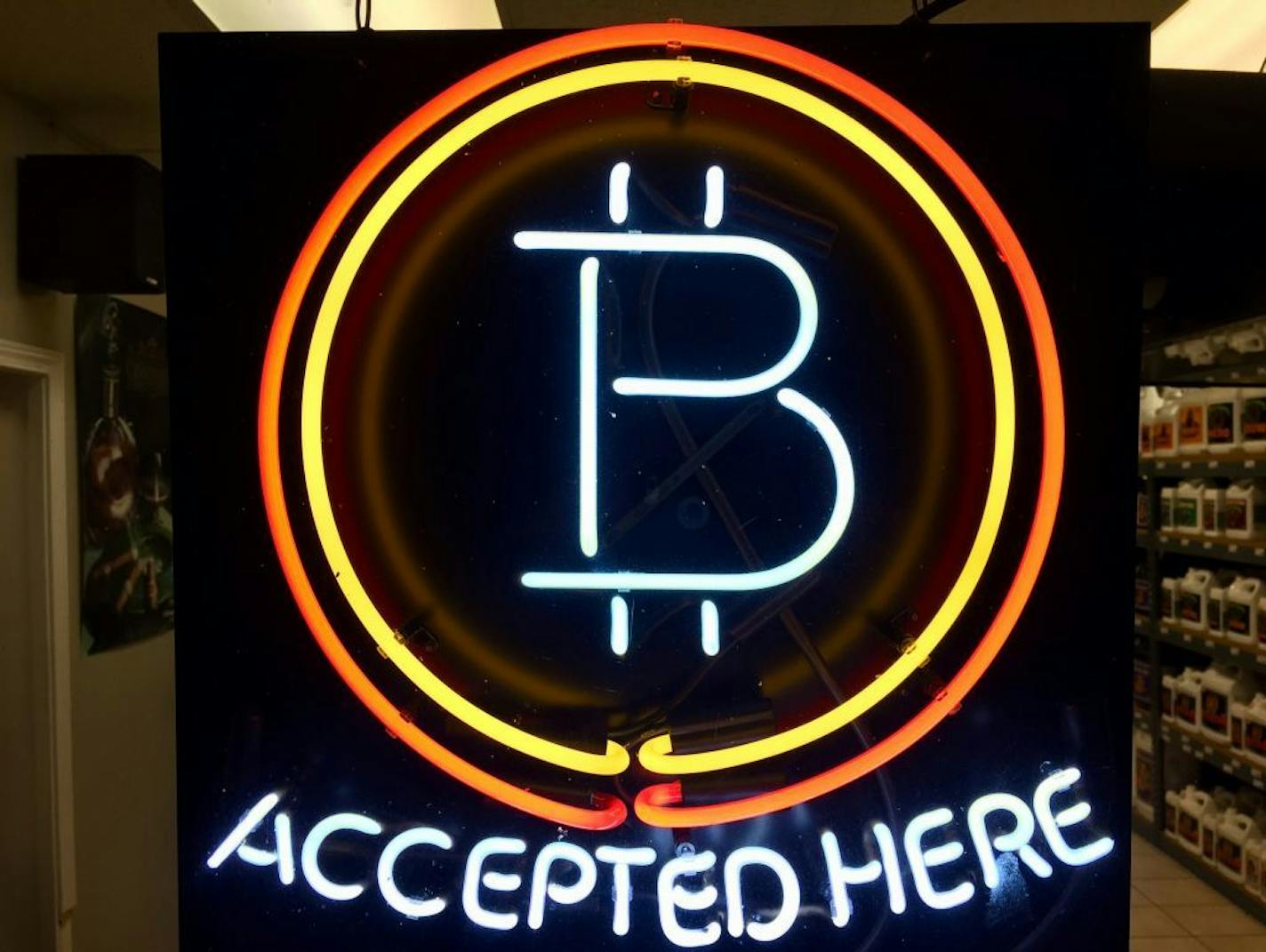 FILE - In this Feb. 7, 2018 file photo, a neon sign hanging in the window of Healthy Harvest Indoor Gardening in Hillsboro, Ore., shows that the business accepts bitcoin as payment. A raft of recent cyber-security firms and governments now cite the rising trend of 'crypto-jacking' _ in which devices are infected with invisible malicious cryptocurrency mining software that uses the computing power of victims' devices to mine virtual currency _ as the main cyber security threat to businesses and c