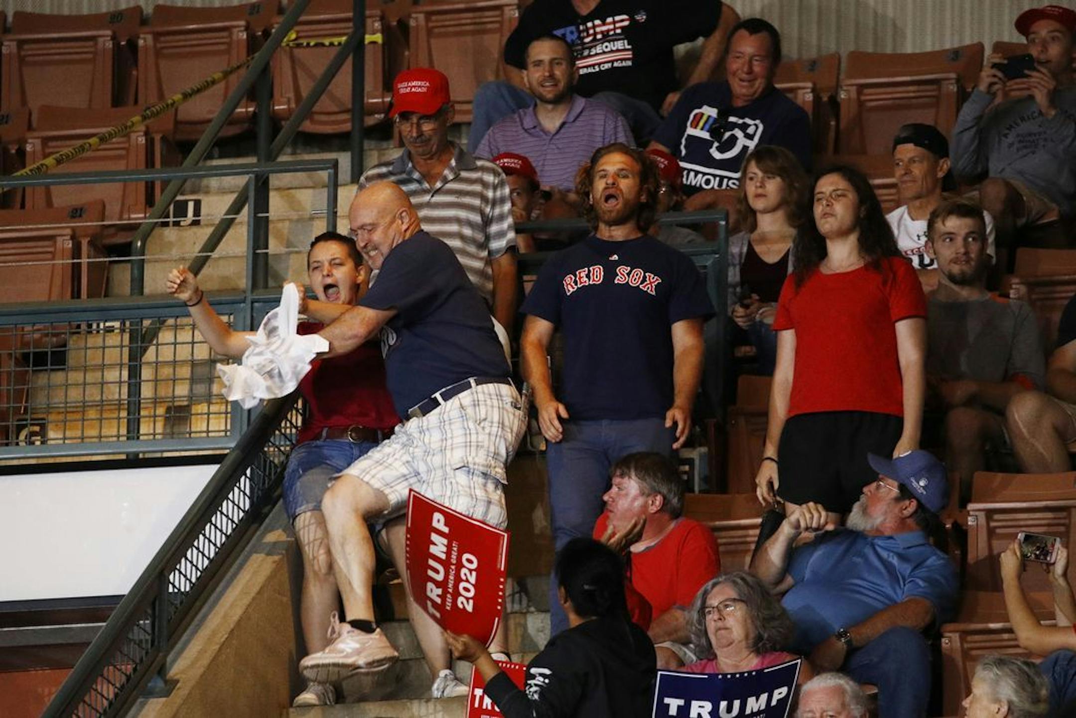 A Trump supporter, center, grabs a protesters' sign as President Donald Trump speaks at a campaign rally, Thursday, Aug. 15, 2019, in Manchester, N.H.