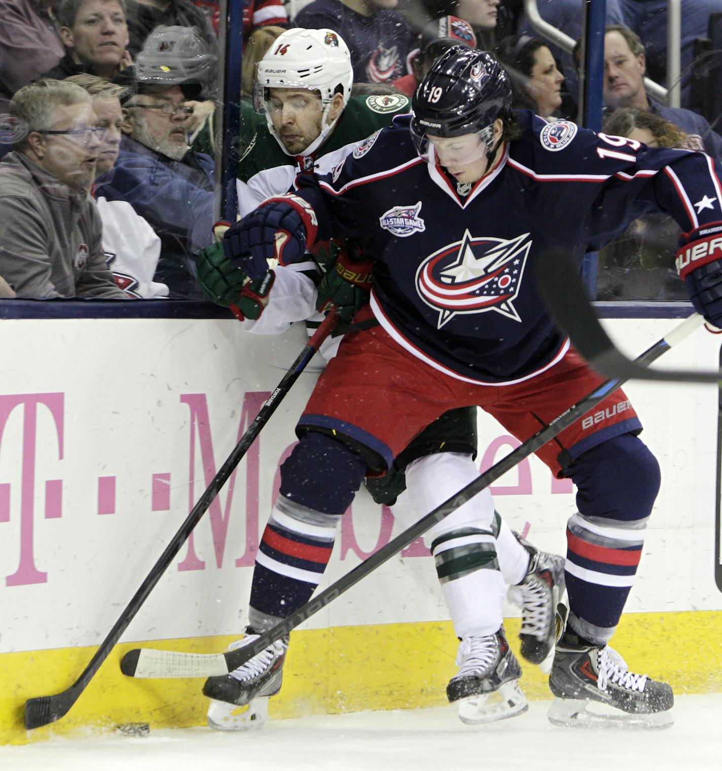 Minnesota Wild's Justin Fontaine, left, and Columbus Blue Jackets' Ryan Johansen fight for a loose puck during the first period of an NHL hockey game Wednesday, Dec. 31, 2014, in Columbus, Ohio. (AP Photo/Jay LaPrete)