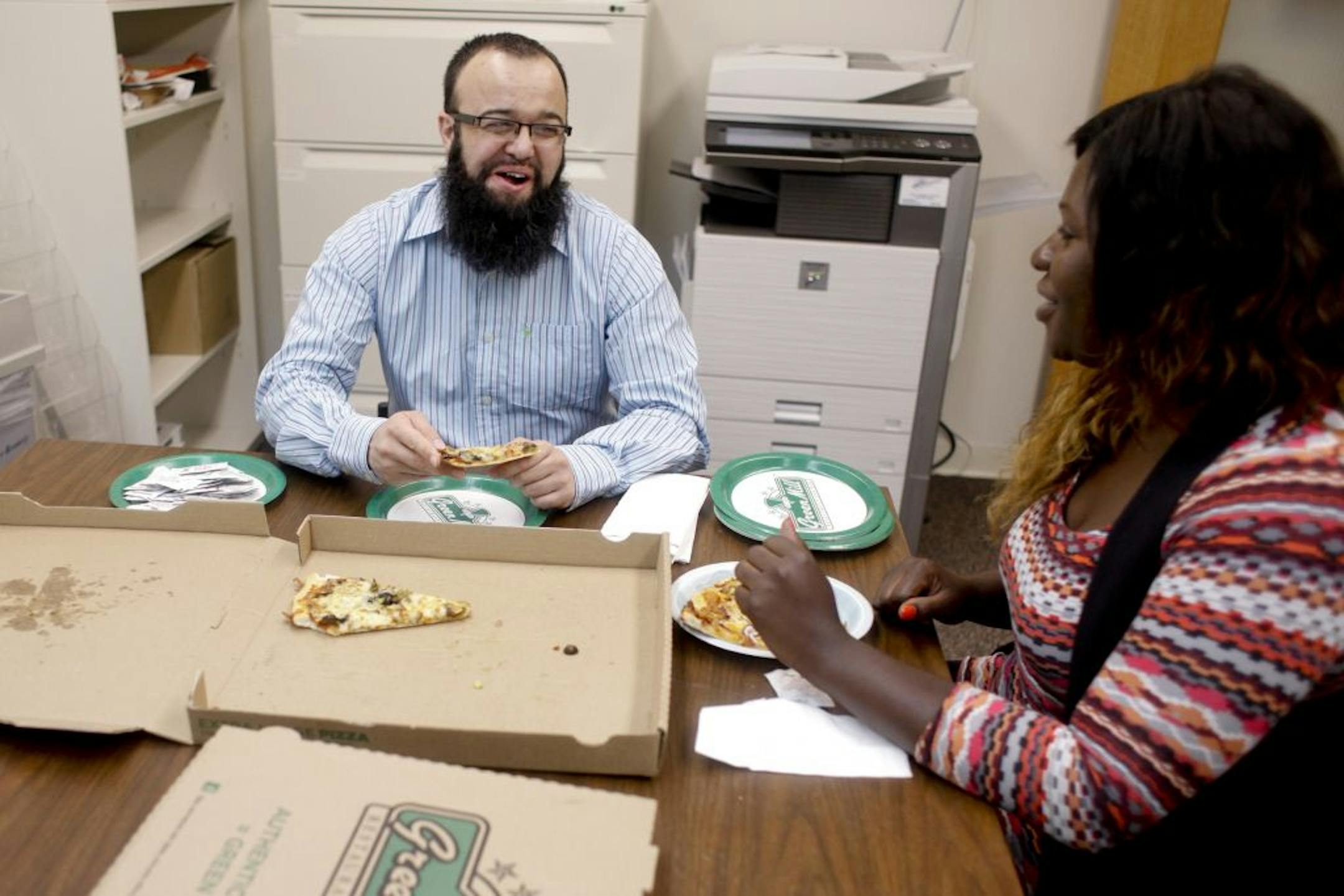 Mohammad Zafar and student worker Angelica Easterling dined on pizza. His department moved a pizza party to allow Zafar to eat with co-workers.