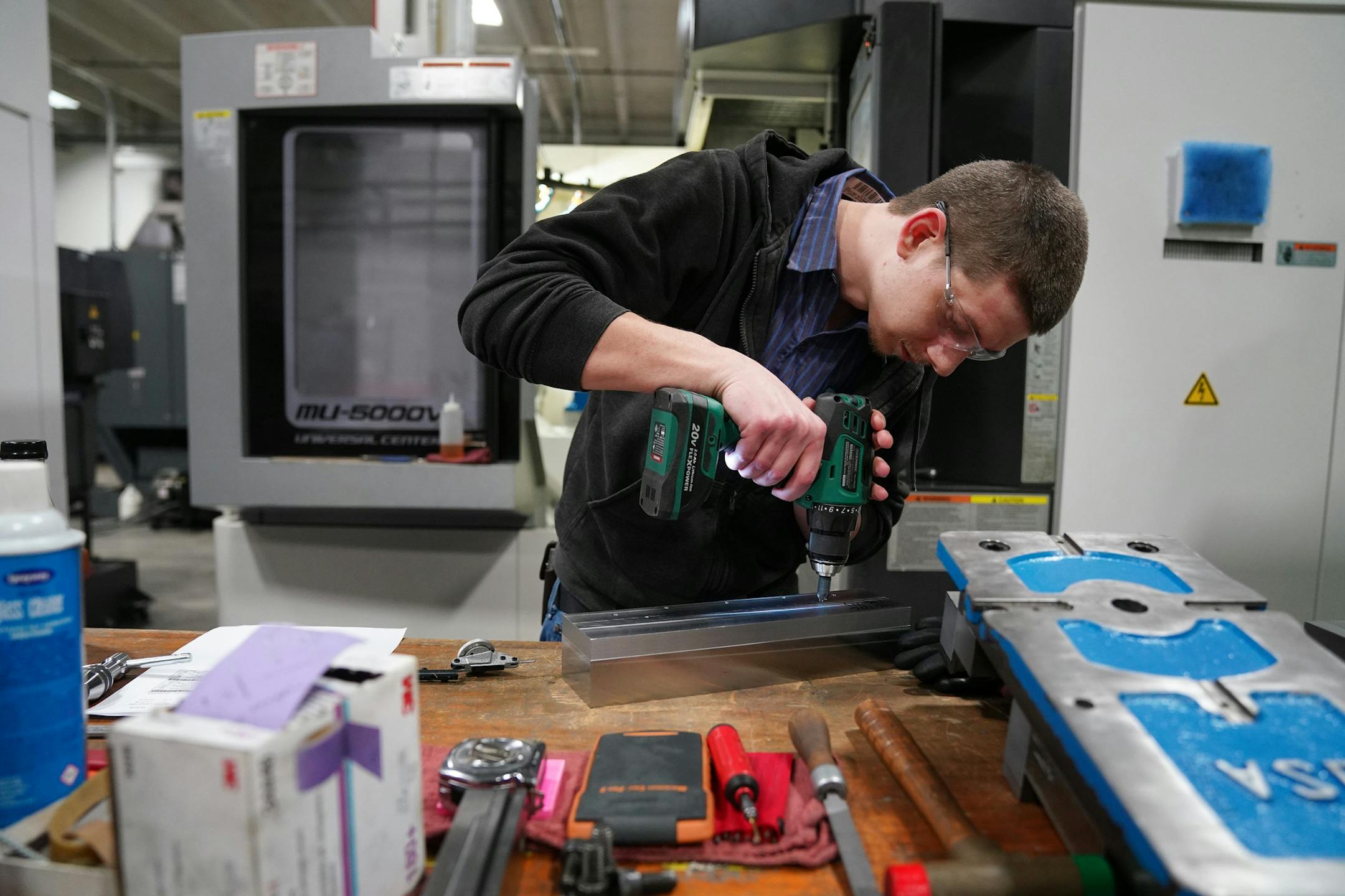 Machinist Derrik Richardson prepped a piece for the 5-axis computer numerical controlled milling machine behind him to fabricate various parts for the aerospace industry. ] ANTHONY SOUFFLE • anthony.souffle@startribune.com Interview and tour with MRG Tool and Die president Rod Gramse of his facilities to discuss manufacturing on the job training Wednesday, Jan. 23, 2020 in Faribault, Minn.