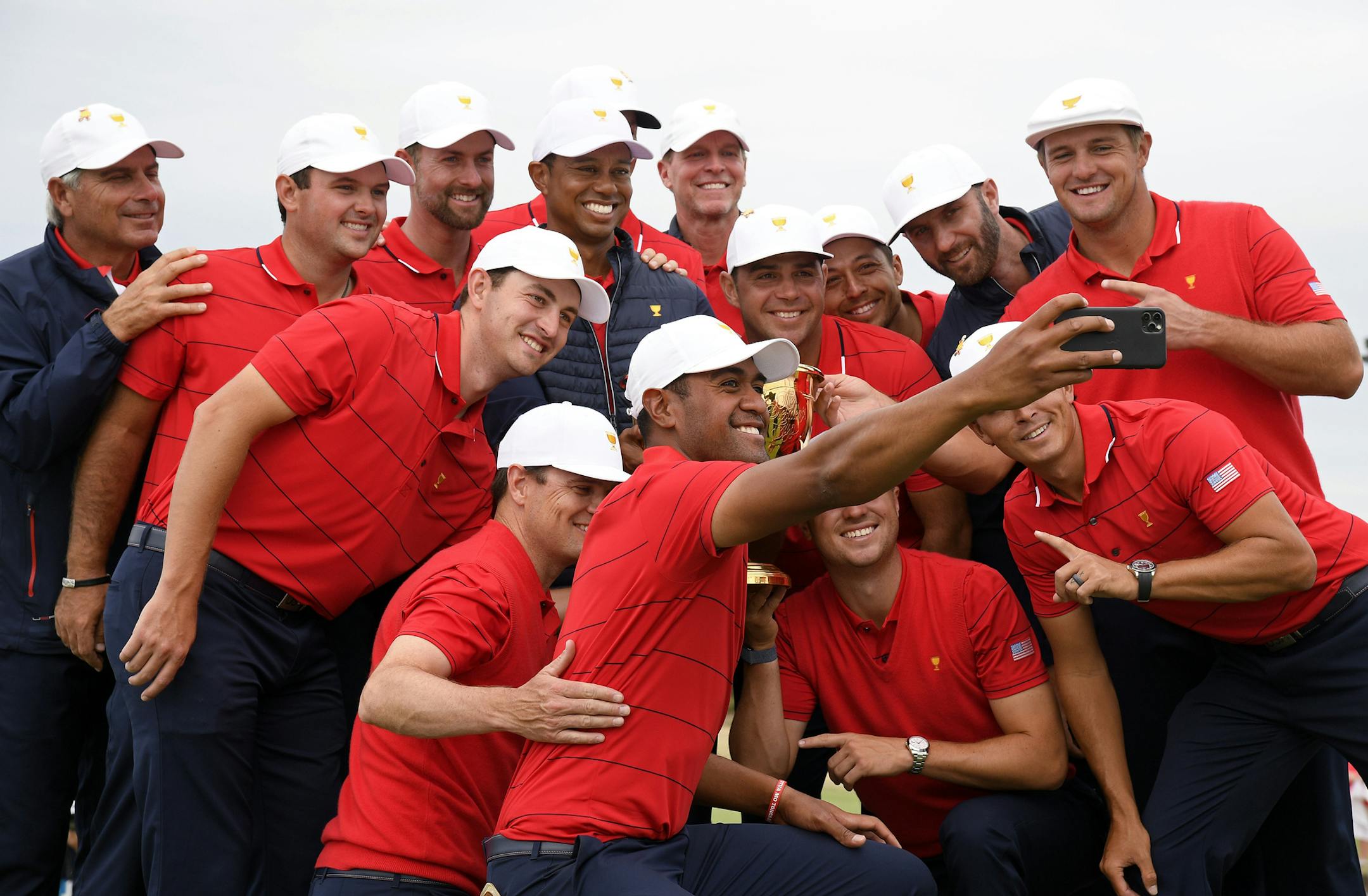U.S. team player Tony Finau, center bottom, uses a phone to photograph teammates and the trophy after winning the President's Cup golf tournament at Royal Melbourne Golf Club in Melbourne, Sunday, Dec. 15, 2019. The U.S. team won the tournament 16-14. (AP Photo/Andy Brownbill)
