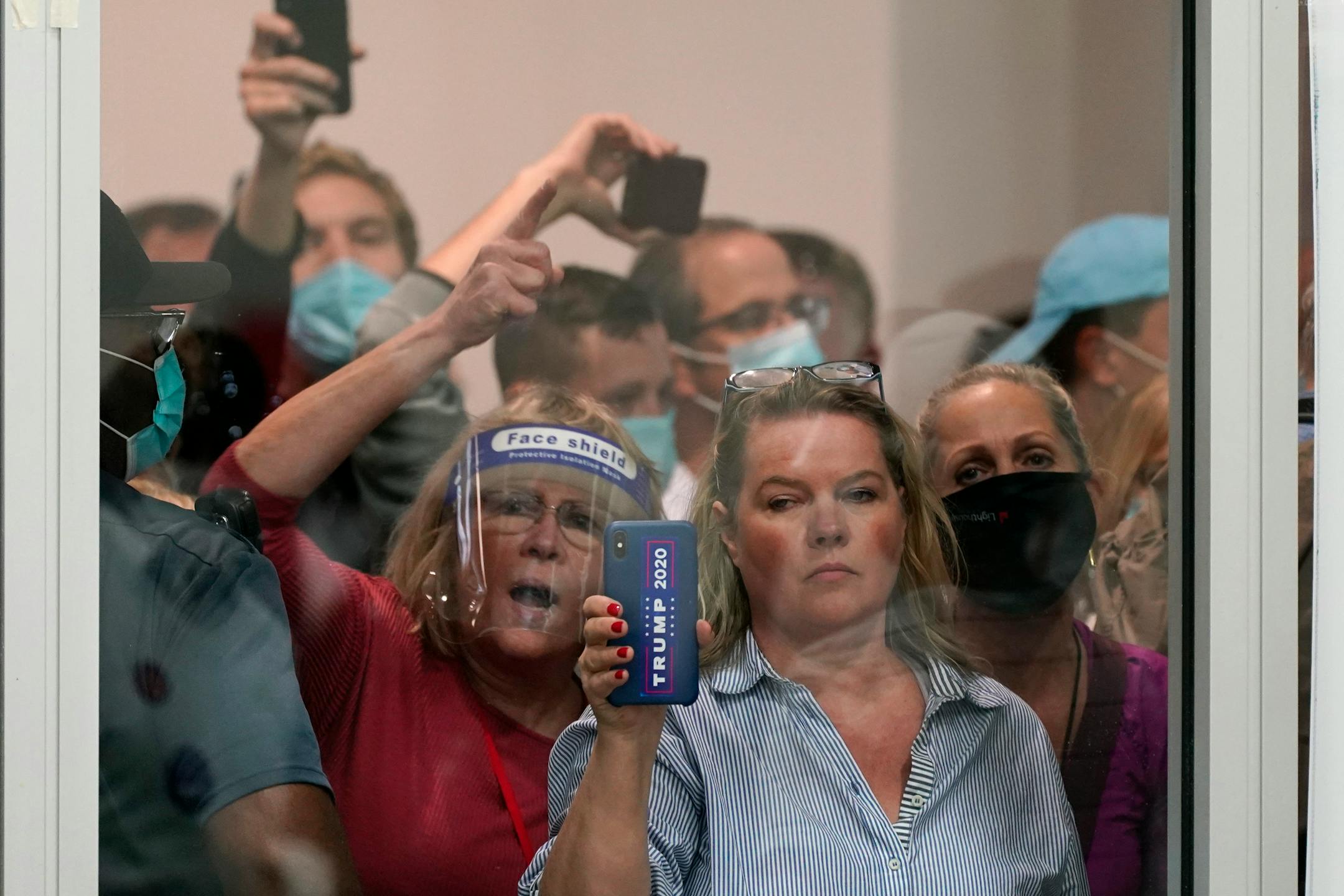 People wanting to be election challengers yell as they look through the windows of the central counting board as police were helping to keep additional challengers from entering due to overcrowding, Wednesday, Nov. 4, 2020, in Detroit. (AP Photo/Carlos Osorio)