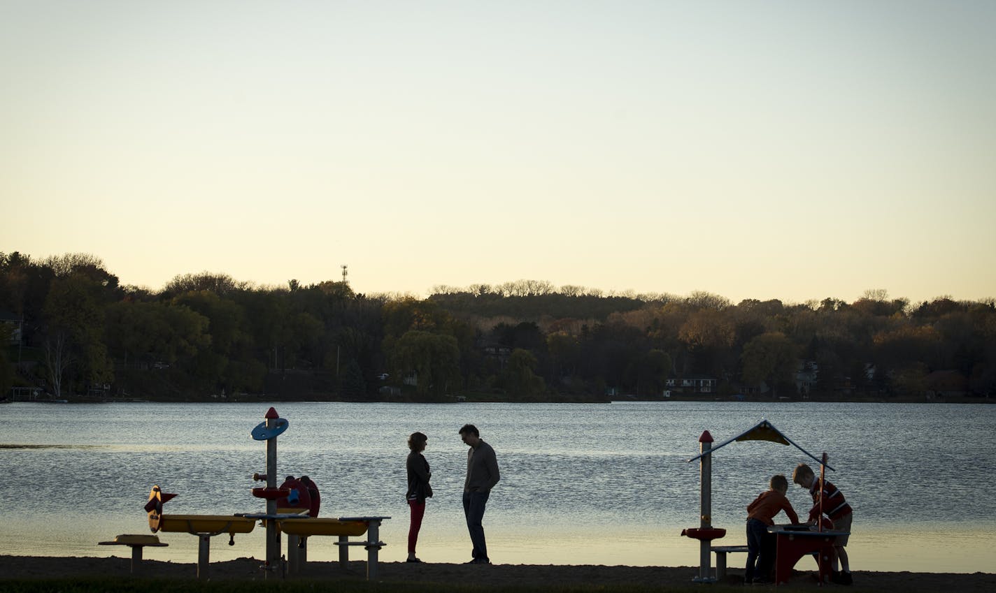 Jennifer and Mike Eastman-Loupe stood by the shore of McCarrons Lake as their two boys played nearby on Tuesday night. ] (AARON LAVINSKY/STAR TRIBUNE) aaron.lavinsky@startribune.com Runoff polluted with lawn chemicals and road salt pour into McCarrons Lake fueling algae growth that chokes other plants and wildlife. A new project will soon divert as much as 1.3 million gallons of that runoff from the lake. Rainwater will be captured, filtered and used to water the playing fields at Upper Villa Pa