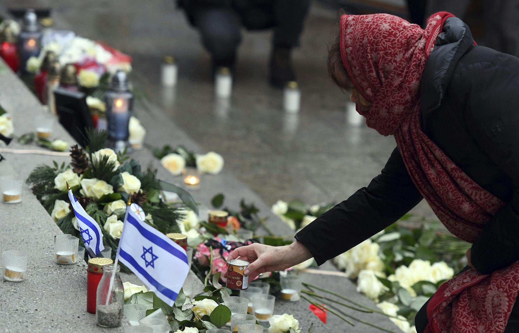 Pedestrians place flowers, pictures and candles after the opening of a memorial site in Berlin, Germany, Tuesday, Dec. 19, 2017 to honor the victims of the Christmas market terrorist attack on the Breitscheid square at the Kaiser Wilhelm Memorial Church one year ago. (Maurizio Gambarini/dpa via AP)