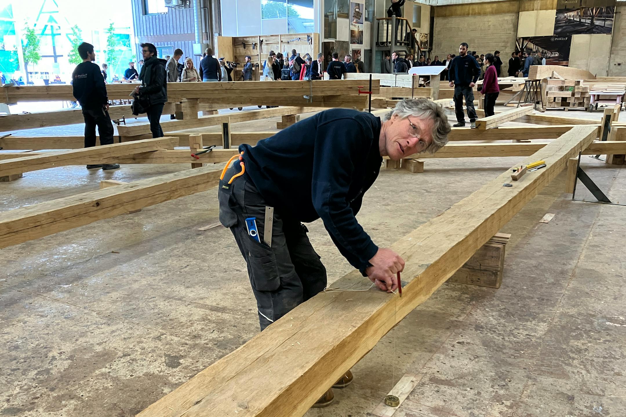 Peter Henrikson, 61, a timber framer from Minnesota, measures a beam, part of the new roof of the Notre Dame cathedral de Paris, Thursday, May, 25, 2023., near Angers, western France. Carpenters building a new timber frame for the fire-ravaged roof of Paris' Notre Dame Cathedral are using the same tools and techniques as their medieval predecessors. For them, working with hand-axes to fashion oak beams has been like stepping back in time. (AP Photo/Jeffrey Schaeffer)