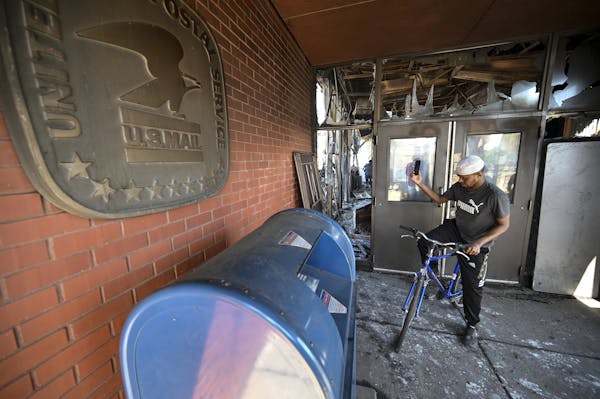 A man took photos of the burnt down U.S. post office across from the Minneapolis Police Fifth Precinct on Saturday.