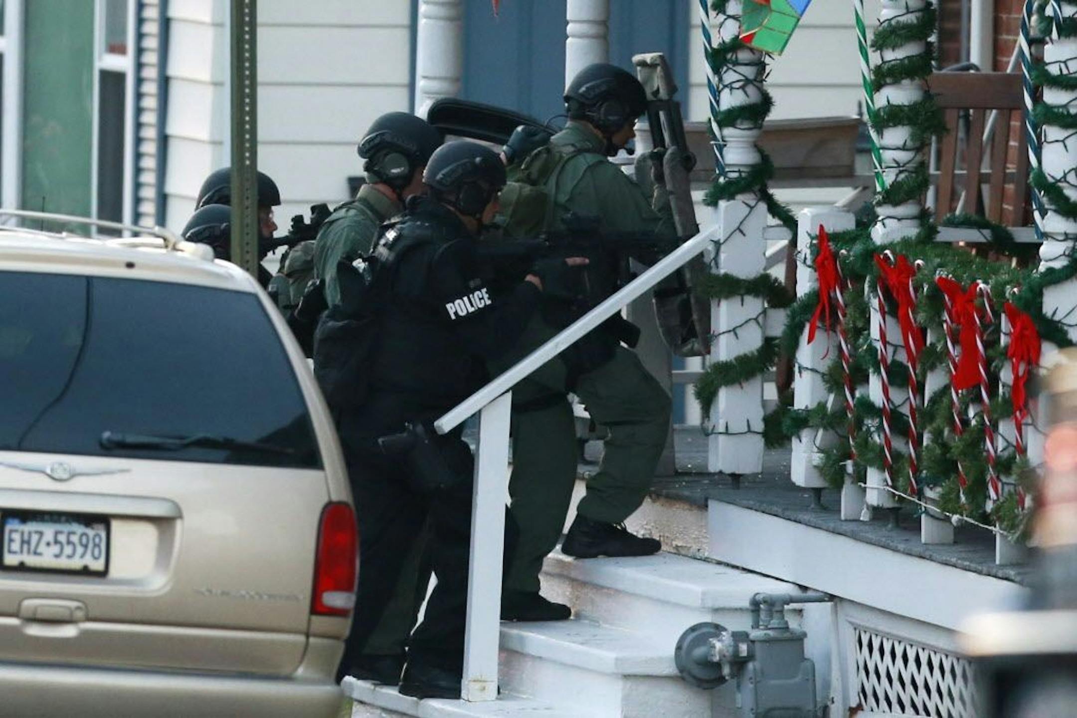 Police gather near a home, Monday, Dec. 15, 2014, in Pennsburg, Pa., where suspect Bradley William Stone is believed to have barricaded himself inside after shootings at multiple homes. The man killed six people and seriously wounded another in three different homes outside Philadelphia and remained at large hours after the shootings, authorities said Monday.