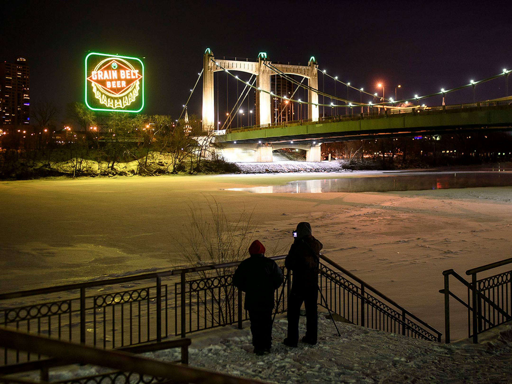 Photographers took photos across the Mississippi from the Grain Belt sign Saturday night after a relighting ceremony.