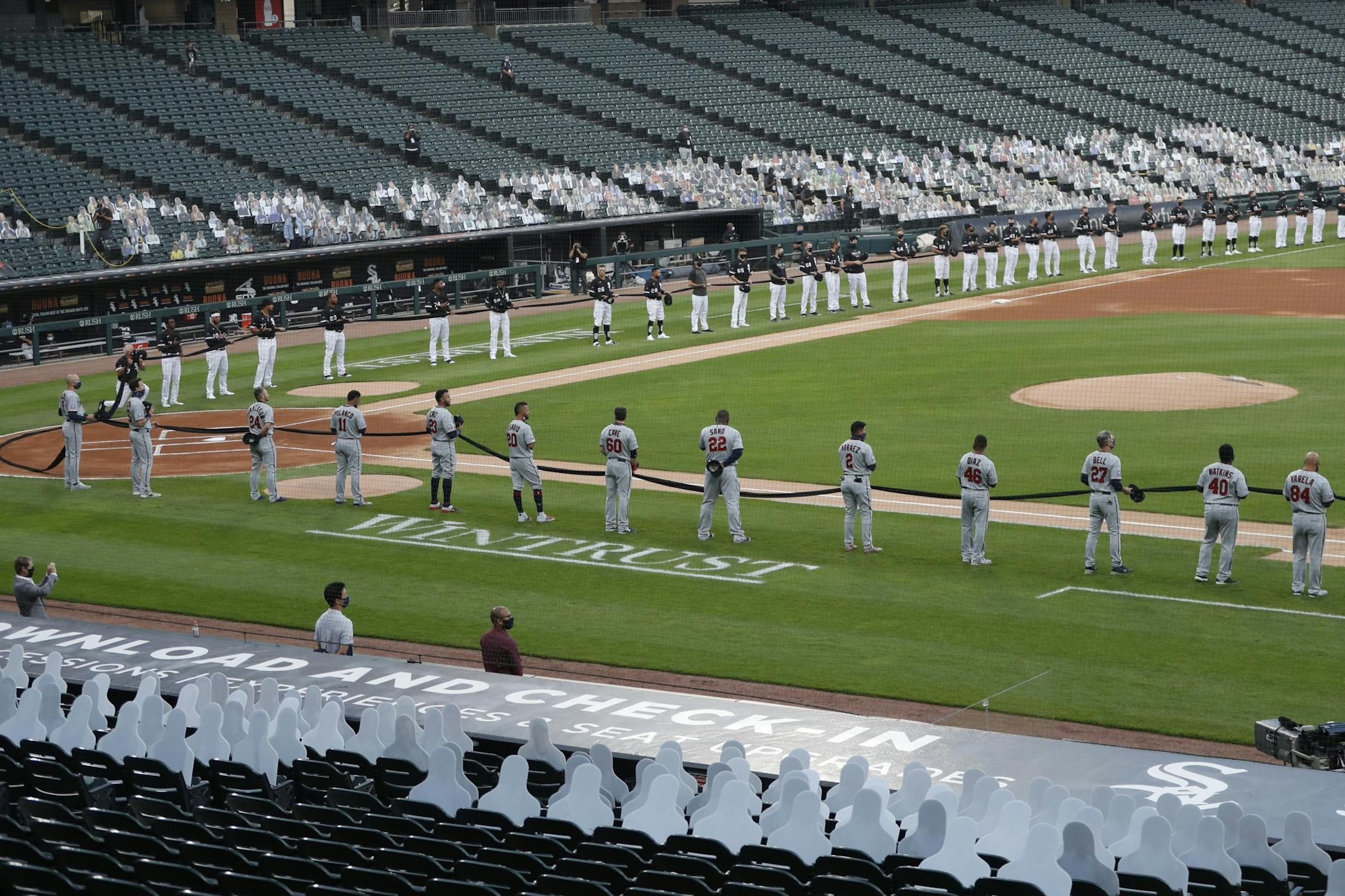 The Chicago White Sox, top, and Minnesota Twins hold a black ribbon for social justice before the White Sox's home opener baseball game Friday, July 24, 2020, in Chicago.
