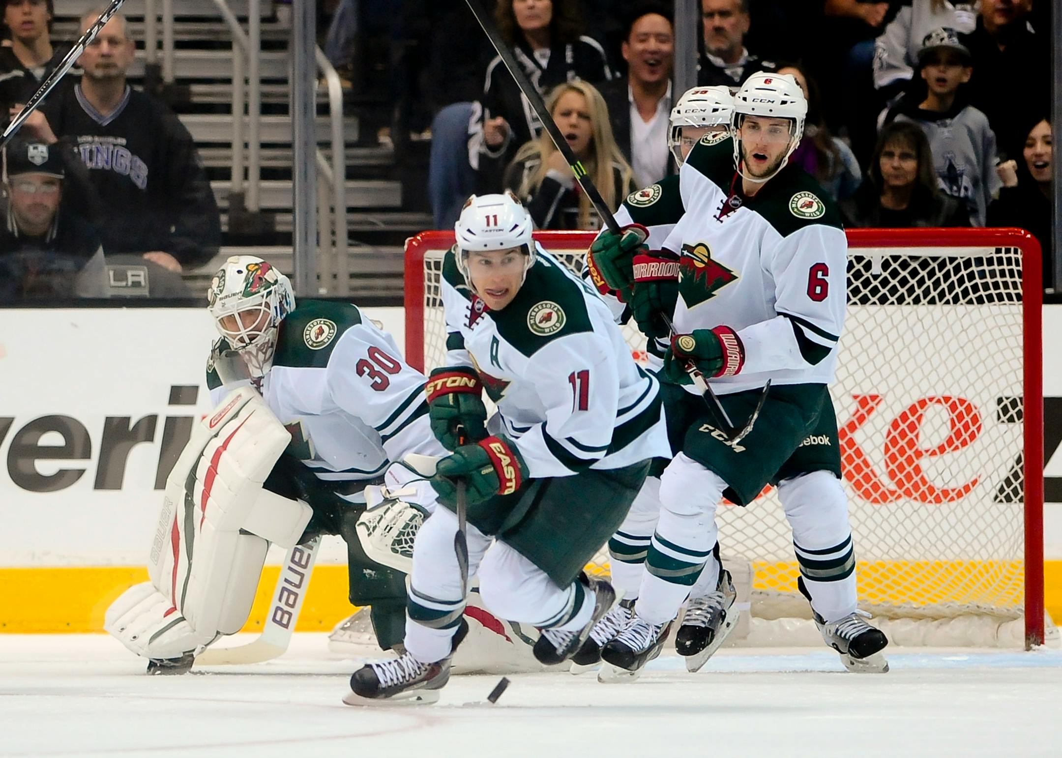 Minnesota Wild left wing Zach Parise (11) and defenseman Marco Scandella (6) help goalie Ilya Bryzgalov (30), of Russia, as a shot is taken during the first period of an NHL hockey game against the Los Angeles Kings, Monday, March 31, 2014, in Los Angeles. (AP Photo/Gus Ruelas)