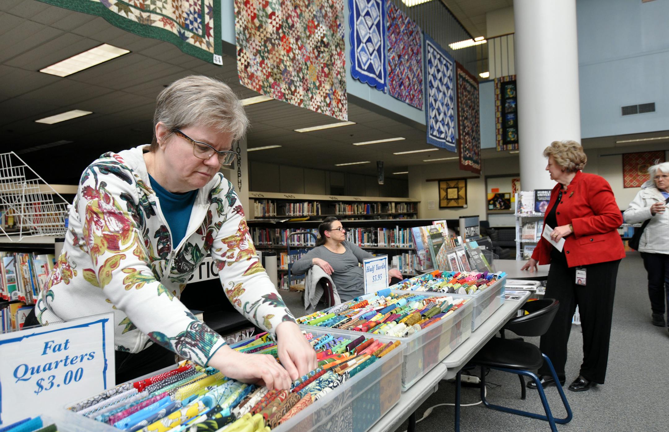 Photo by Liz Rolfsmeier Mindy Way-Johnson, of White Bear Lake, sorted fabric at a booth for Twin Cities Quilting of Roseville, while shop owner Faye Hock chatted with Laura Nagel, organizer of ìQuilt Connections,î Eagan High Schoolís 19th annual quilt exhibit honoring Women's History Month.