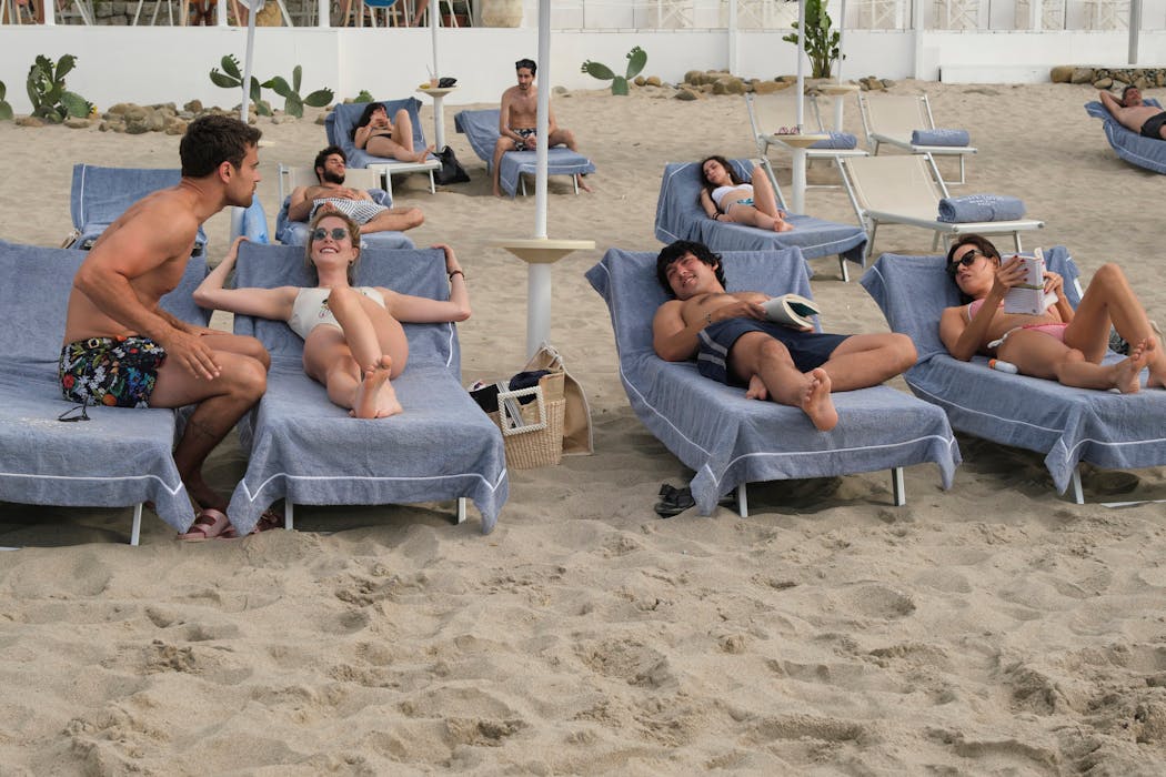 Theo James as Cameron Sullivan, Meghann Fahy as Daphne Sullivan, Will Sharpe as Ethan Spiller, and Aubrey Plaza as Harper Spiller hang out on the beach in Taormina in Season 2, Episode 1 of HBO’s “The White Lotus.” 