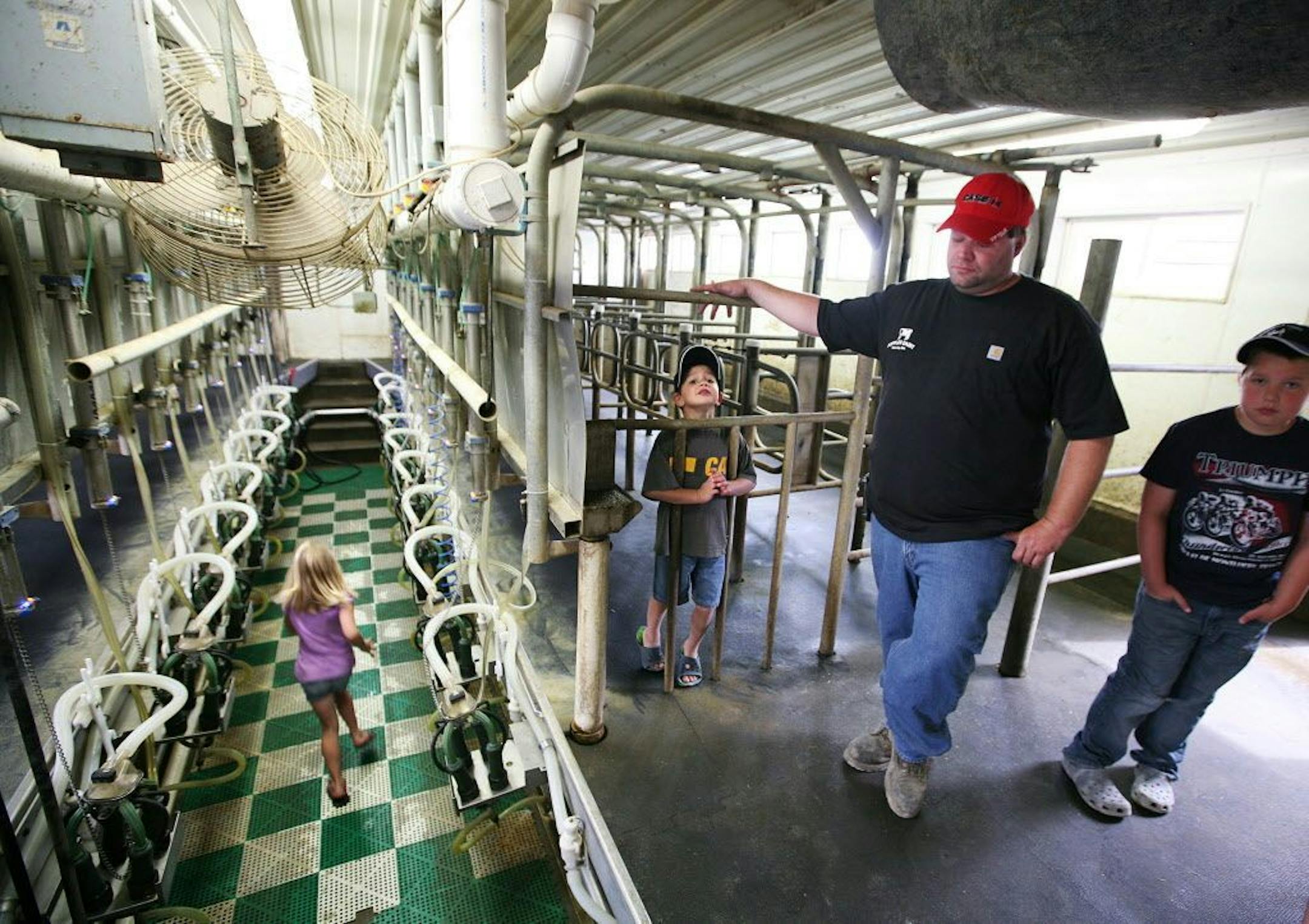 While his children, left to right, Dani, 7, Shayne, 5, and Brett, 10, play in the milking parlor, dairy farmer Harlan Poppler gets emotional as he considers the many dead cows he had to carry out of his barns over recent years at Poppler Dairy Farm in Waverly July 25, 2013. His cows were affected by stray currents from a local electric company.