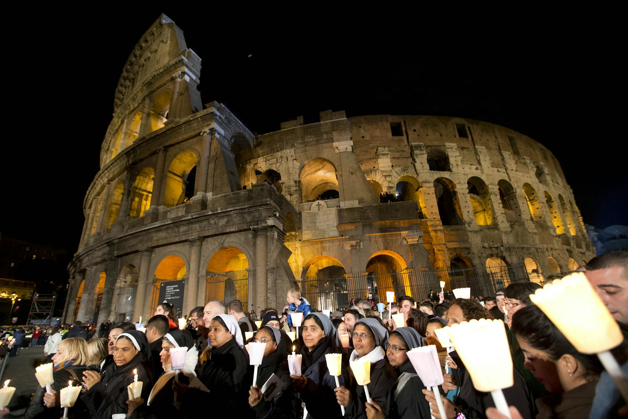 Nuns and faithful hold candles as they attend the Via Crucis (Way of the Cross) torchlight procession celebrated by Pope Francis in front of the Colosseum on Good Friday, in Rome, Friday, April 3, 2015. (AP Photo/Andrew Medichini)
