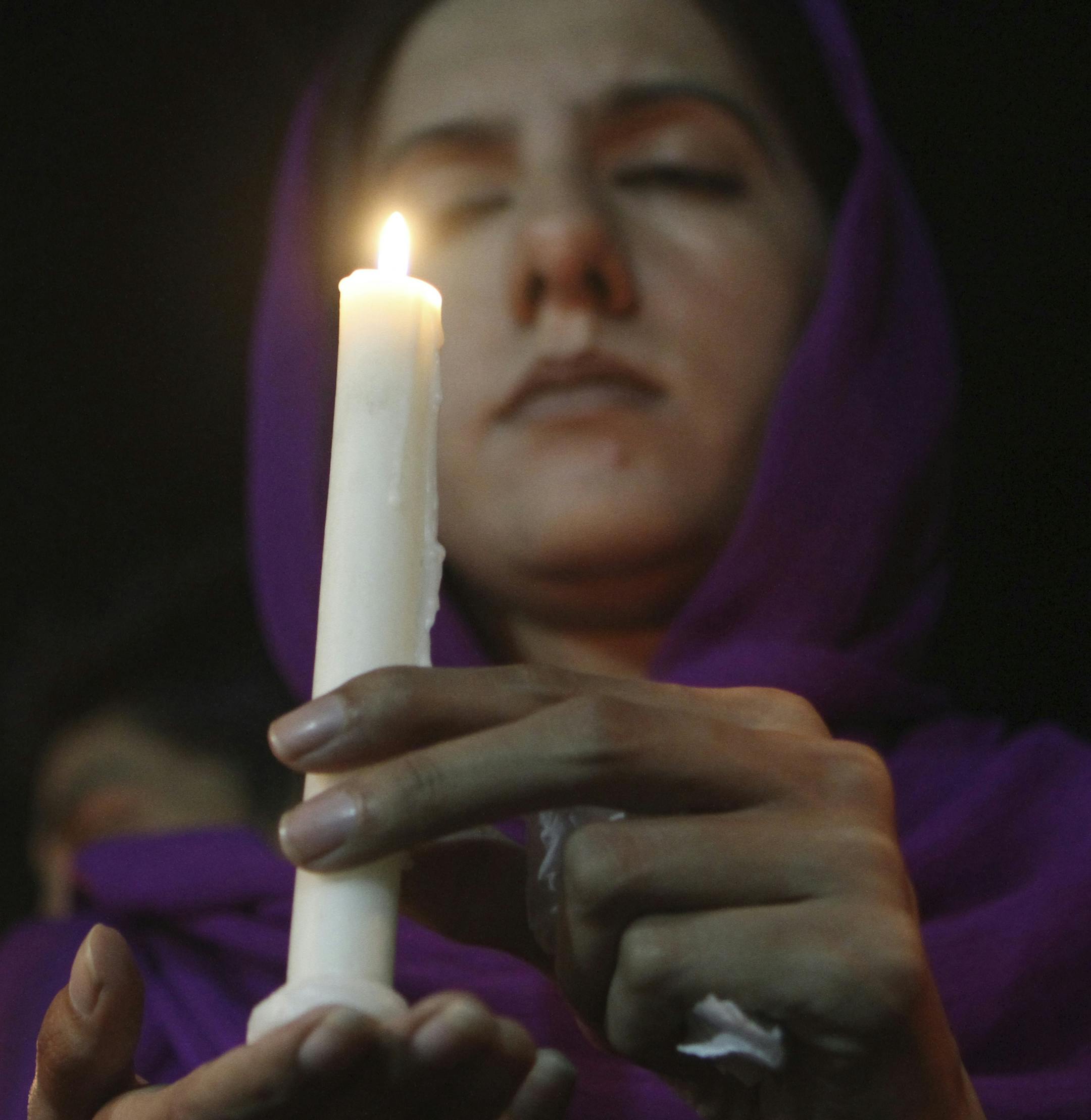 A Pakistani woman holds a candle for the passengers of a Malaysia Airlines plane which disappeared on March 8, while holding a candlelight vigil organized by Peace for Life Welfare Foundation in Lahore, Pakistan, Thursday, March 20, 2014. An air search in the southern Indian Ocean for possible objects from the missing Malaysia Airlines plane described as the “best lead” so far ended for the day without success Thursday but will resume in the morning, Australian rescue officials sai