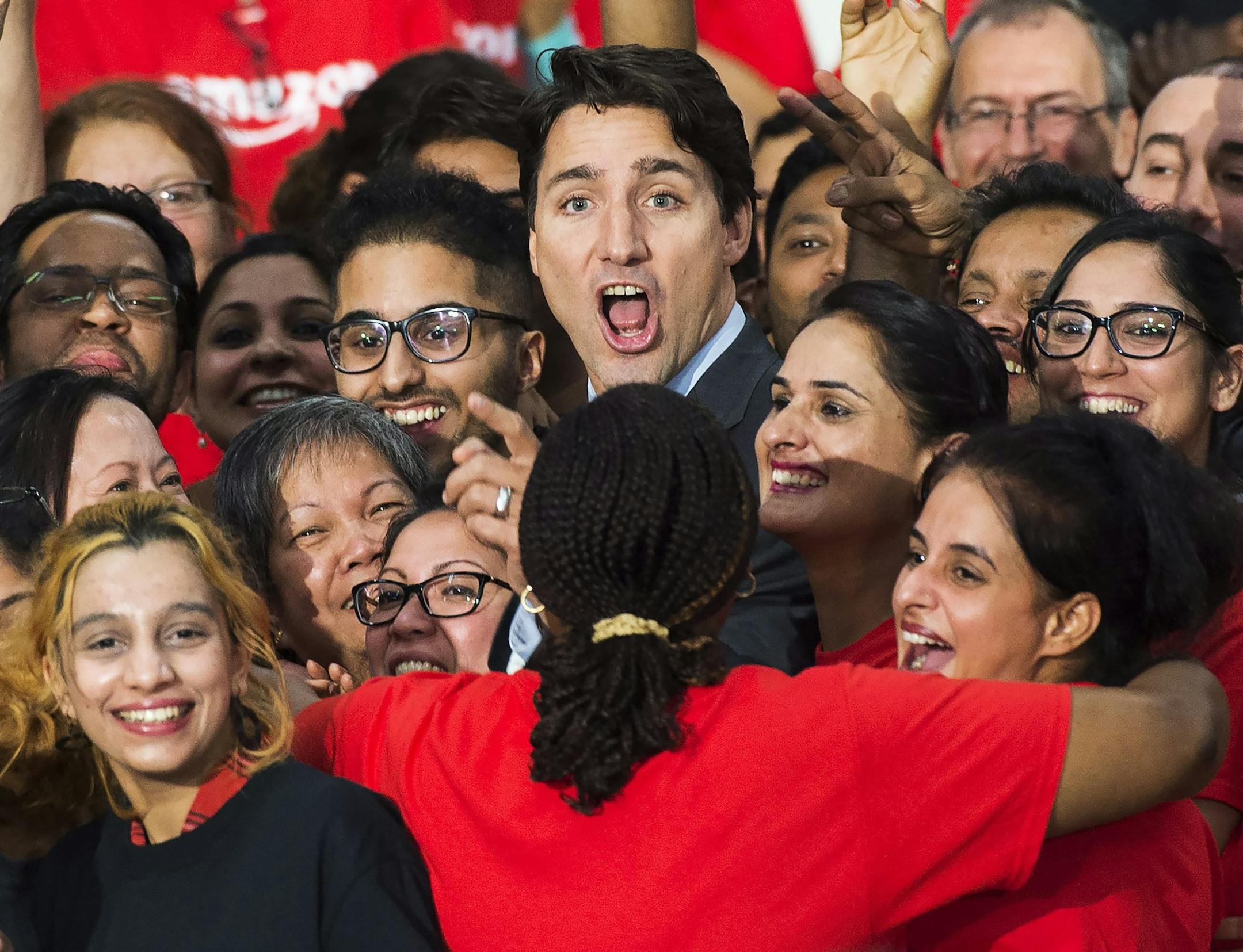 Canada's Prime Minister Justin Trudeau is swarmed by employees at the new Amazon fulfillment center, in Brampton, Ontario, Canada, Thursday, Oct. 20, 2016. Trudeau says the high-tech facility will create more than 700 full-time jobs. (Nathan Denette/The Canadian Press via AP) ORG XMIT: NSD102