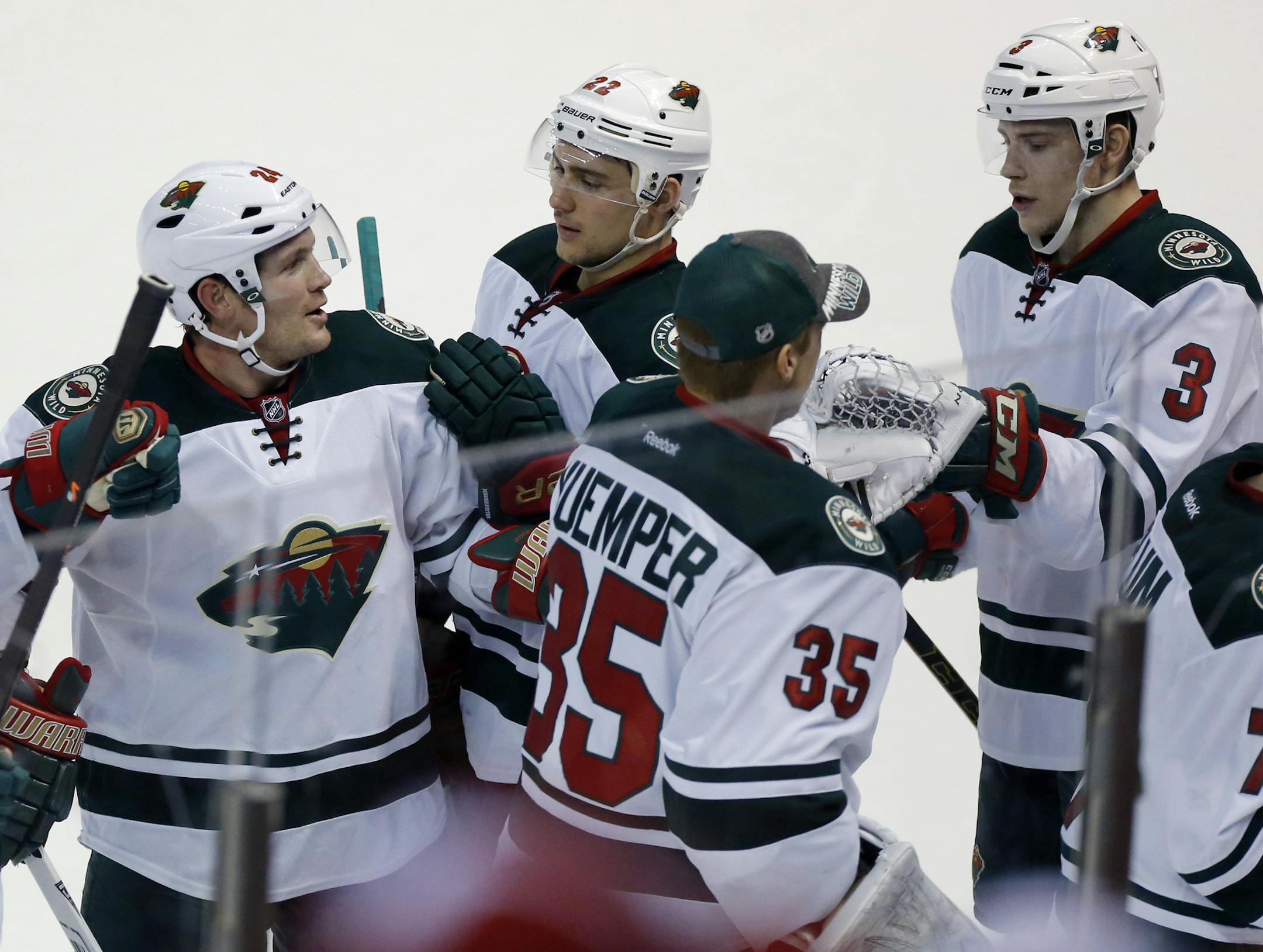 Minnesota Wilds' Charlie Coyle (3) celebrates with teammates Matt Cooke, left, Nino Niederreiter (22), of the Switzerland and Darcy Kuemper (35) after assisting on the game-winning goal in overtime to defeated the Detroit Red Wing 4-3 Sunday, March 23, 2014 in Detroit. (AP Photo/Duane Burleson)