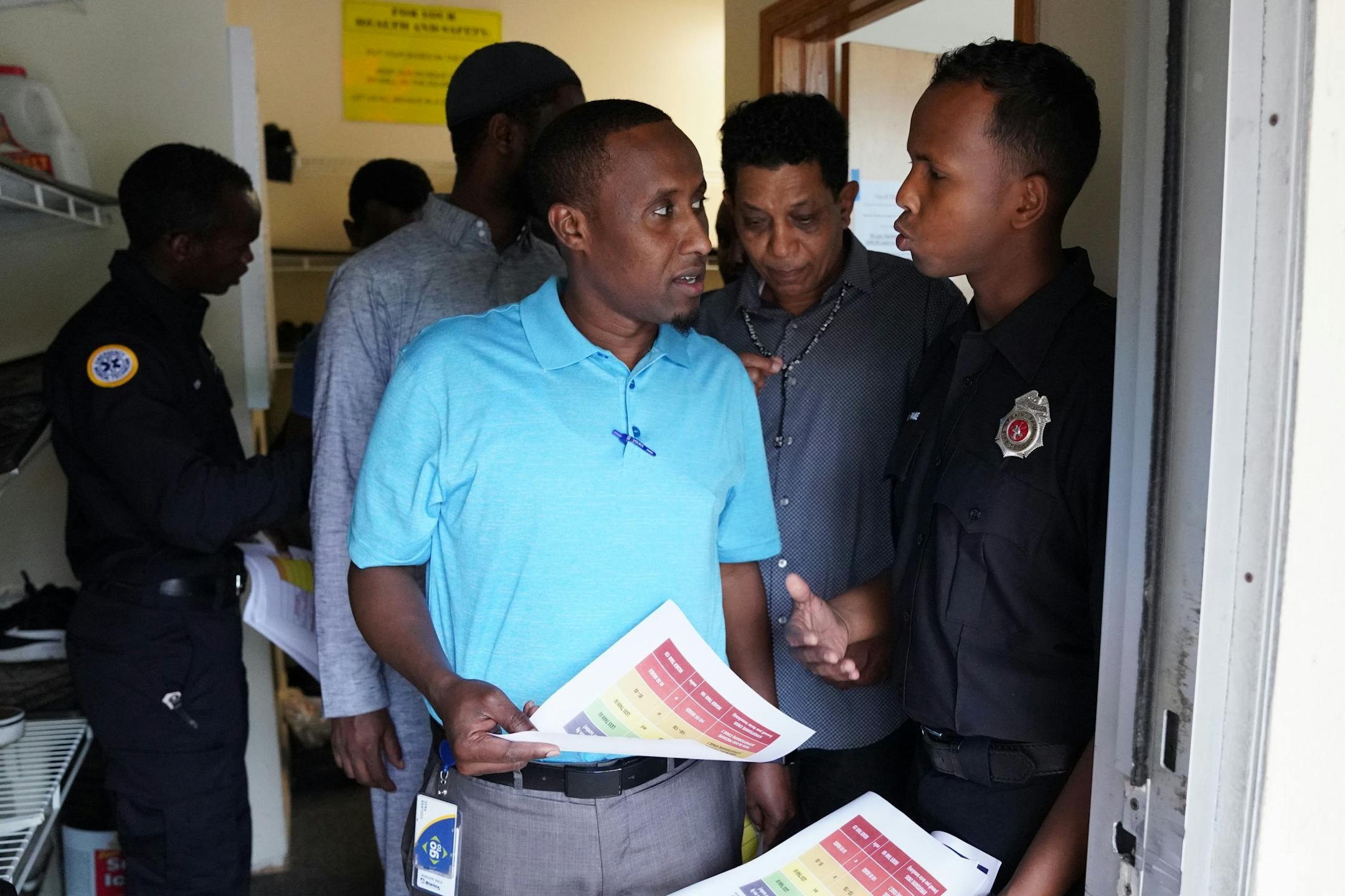 Mohamed Daoud, left, and Abdi Warsame, right, two newly sworn in Somali American firefighters with the St. Paul Fire Department, passed out fliers on topics ranging from preventing kitchen fires to addressing high blood pressure to worshipers at the Islamic Dawah Center as part of their community outreach.