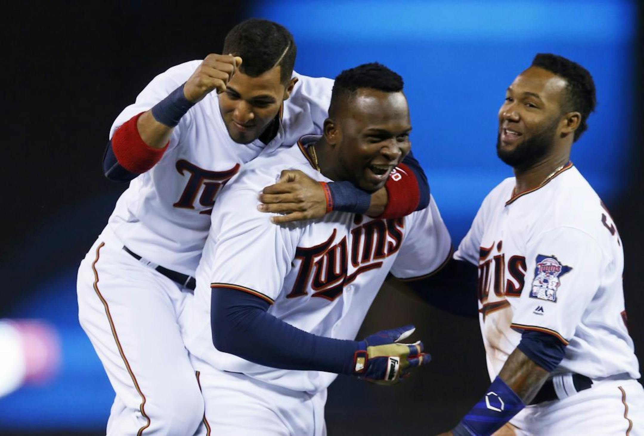 Minnesota Twins' Eddie Rosario, left, and Danny Santana, right, welcome Miguel Sano after his walk-off single gave the Twins a 6-5 win over the Cleveland Indians in a baseball game Tuesday, April 26, 2016, in Minneapolis.