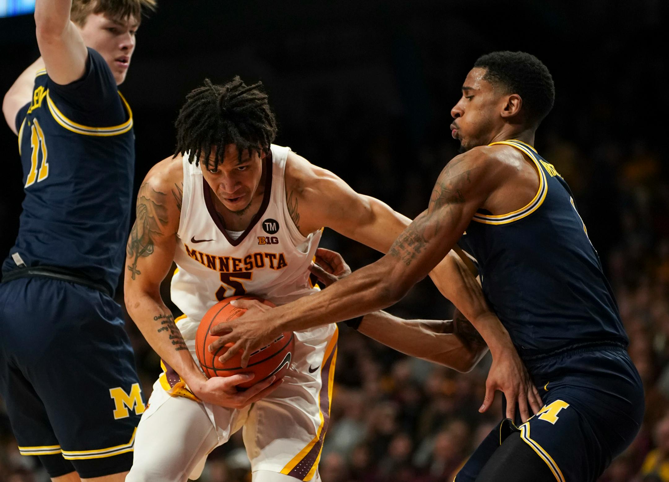 Gophers guard Amir Coffe tried to squeeze between Michigan defenders Colin Castleton, left, and Charles Matthews.