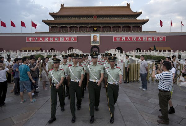 In this May 28, 2014 photo, paramilitary policemen march out of Tiananmen Gate to clear tourists from the area for a flag-lowering ceremony on Tiananm