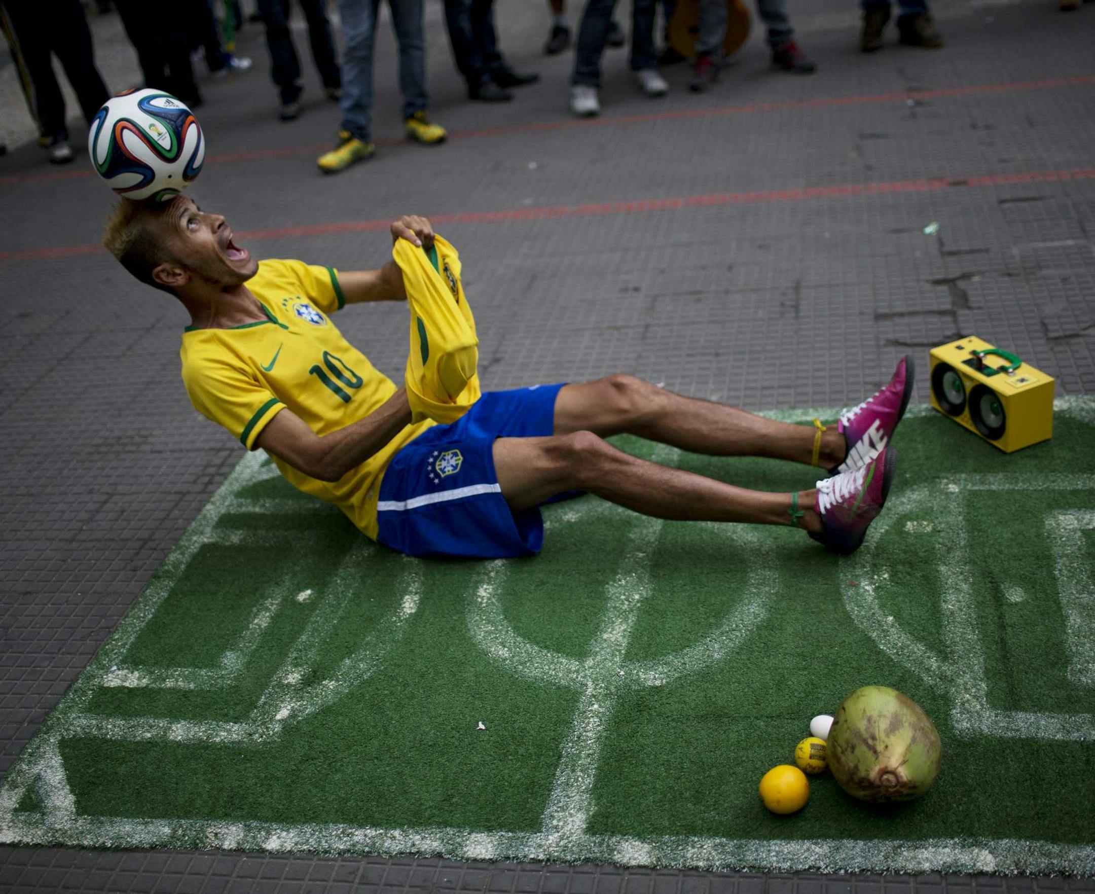A street performer dressed as a Brazilian national soccer team player, balances a ball on his head during his presentation in downtown Sao Paulo, Brazil, Tuesday, June 10, 2014. The 2014 World Cup is set to begin Thursday, with Brazil and Croatia competing in the opening match in Sao Paulo. (AP Photo/Rodrigo Abd)