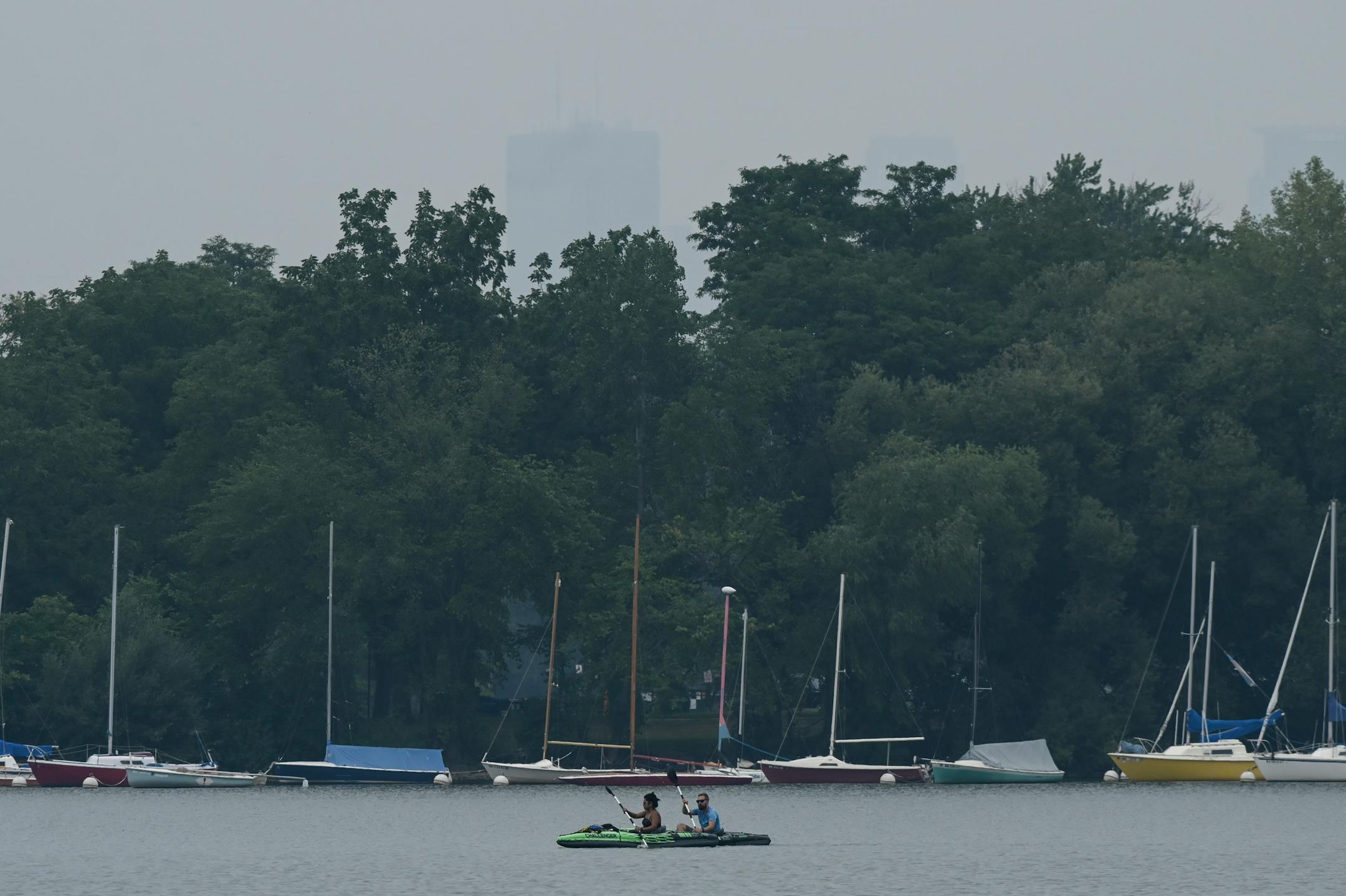 Kayakers paddled along a smoky Lake Nokomis, with a glimpse of downtown Minneapolis.