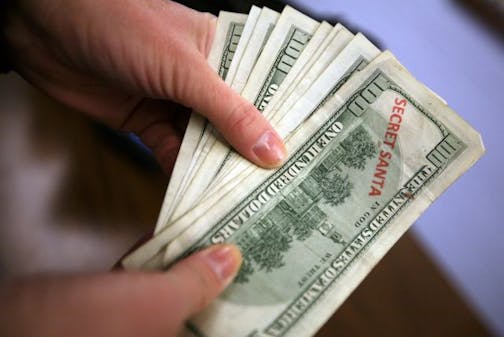 An anonymous secret Santa looks over a stack of hundred dollar bills before giving them out in Lincoln Park, Mich. on Monday, Dec. 22, 2008. A Metro Detroit couple spent the day giving $11,000 to random working people to help make their Christmas better. The couple says they wanted to give money to people impacted by Detroit's struggling auto industry, poor economy, high unemployment and numerous home foreclosures.