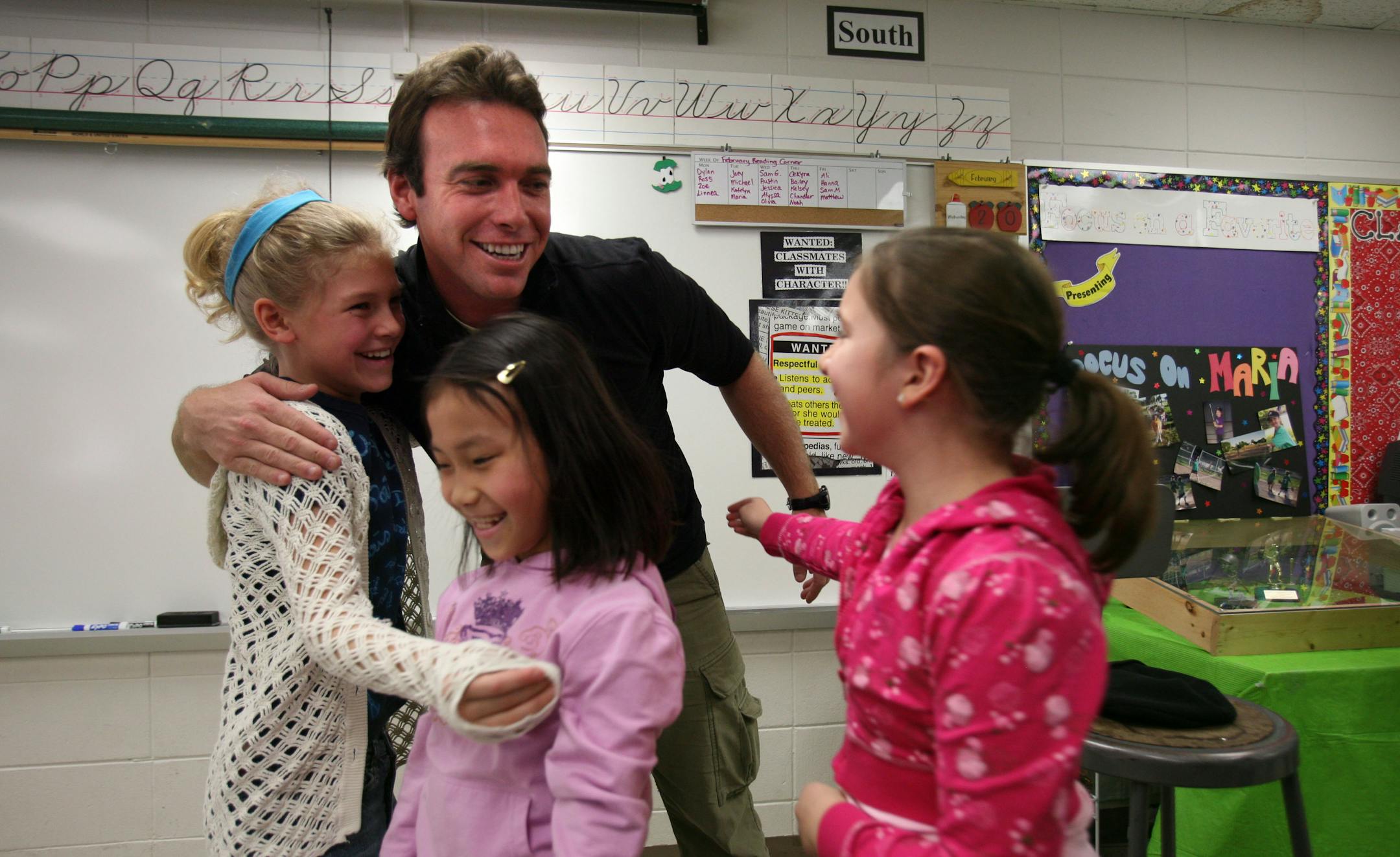 From left, third graders Hanna Mortenson, Zoe Coilan and Linnea Seline hugged Alex Boylan, of "Around the World for Free," as he visited classrooms at Hillside Elementary in Cottage Grove. Boylan spent the day at the school as one of his last stops before the show ends.