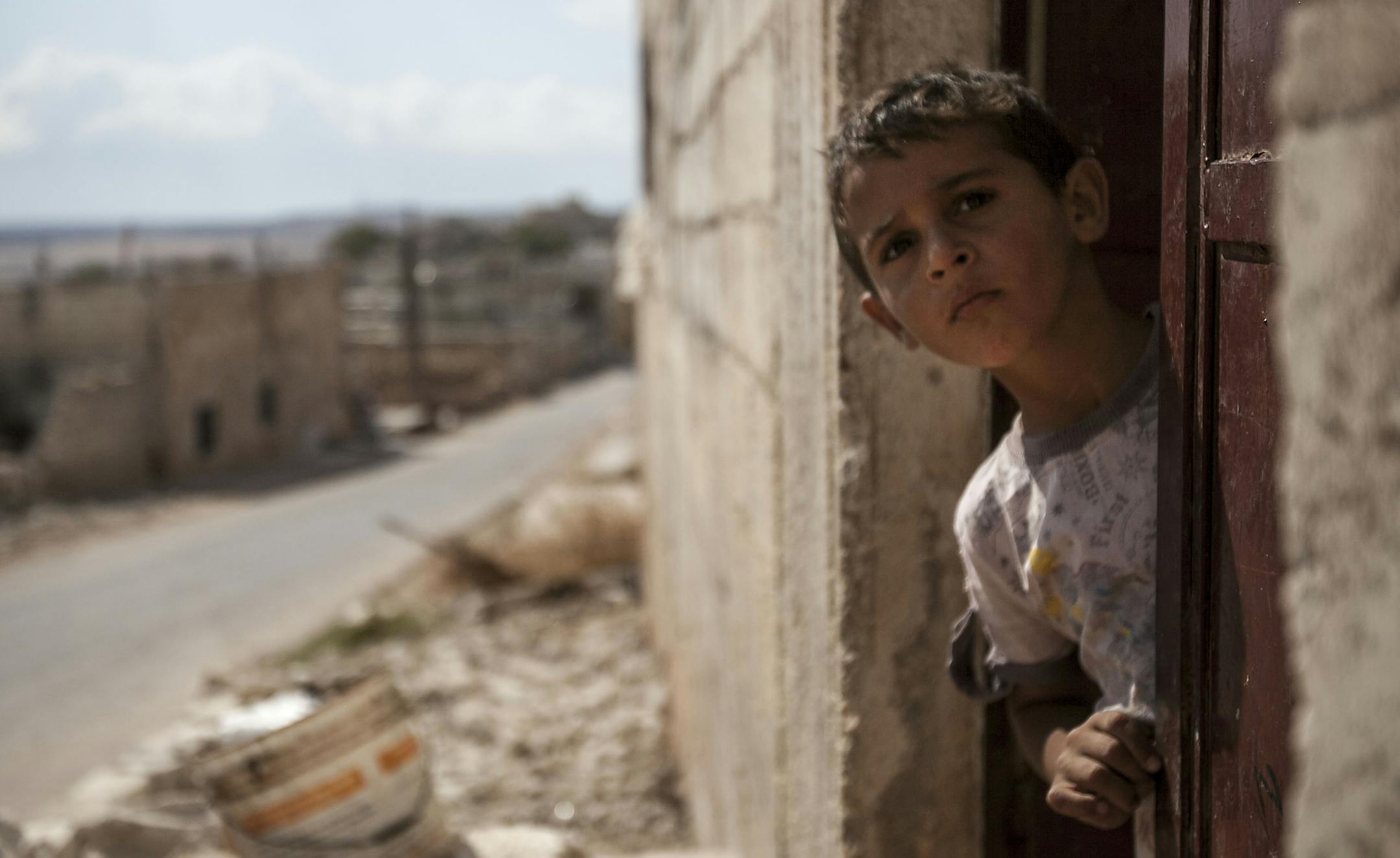 In this Thursday, Sept. 19, 2013 photo, a Syrian child looks out from his home during heavy fighting between troops loyal to President Bashar Assad and opposition fighters, in the Idlib province countryside, Syria. For Syria's divided and beleaguered rebels, the creeping realization that there will not be a decisive Western military intervention on their behalf is a huge psychological blow. It now appears that the regime of Bashar Assad has gained time, largely because the world community is too