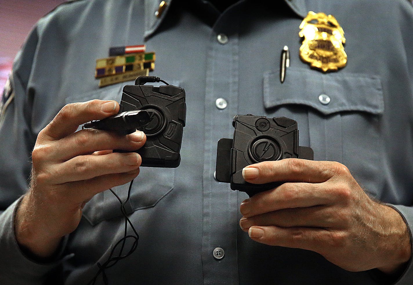 Minneapolis Police Lt. Greg Reinhardt displayed two of the body cameras that will be tested by the department. Both cameras will record 9.5 hours of video (non HD) and are mad by Taser. One camera attaches to an officer&#x201a;&#xc4;&#xf4;s body and is completely self-contained, while the other offers a more flexible option, with a thinner camera attached to a battery. ] JIM GEHRZ &#x201a;&#xc4;&#xa2; jgehrz@startribune.com / Minneapolis, MN / November 7, 2014 / 1:00 PM / BACKGROUND INFORMATION: