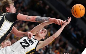 Purdue forward Rickie Woltman, left, knocks the ball away from Iowa guard Caitlin Clark (22) during the first half of an NCAA college basketball game