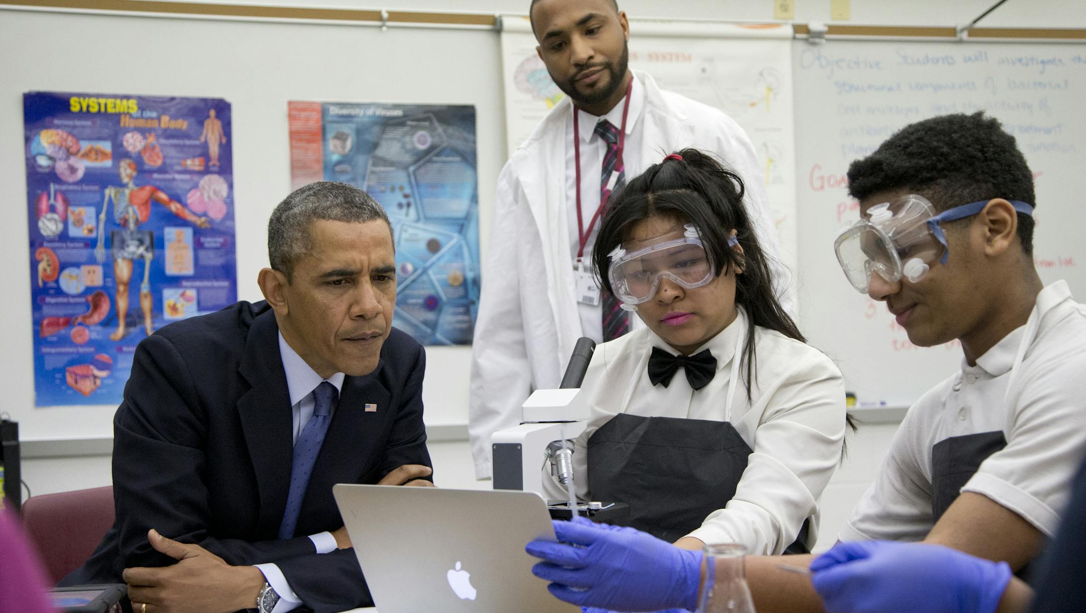 President Barack Obama looks over students' work as he visits a classroom at Bladensburg High School, Monday, April 7, 2014, in Bladensburg, Md., before speaking about the economy and to announce the winners of a competition he launched last fall to bring together educators and employers to redesign the high school experience to give students access to real-world career skills and college-level courses. (AP Photo/Carolyn Kaster)