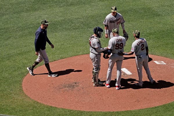 Minnesota Twins manager Rocco Baldelli, left, walks to the mound to make a pitching change during the sixth inning of a baseball game against the Kans