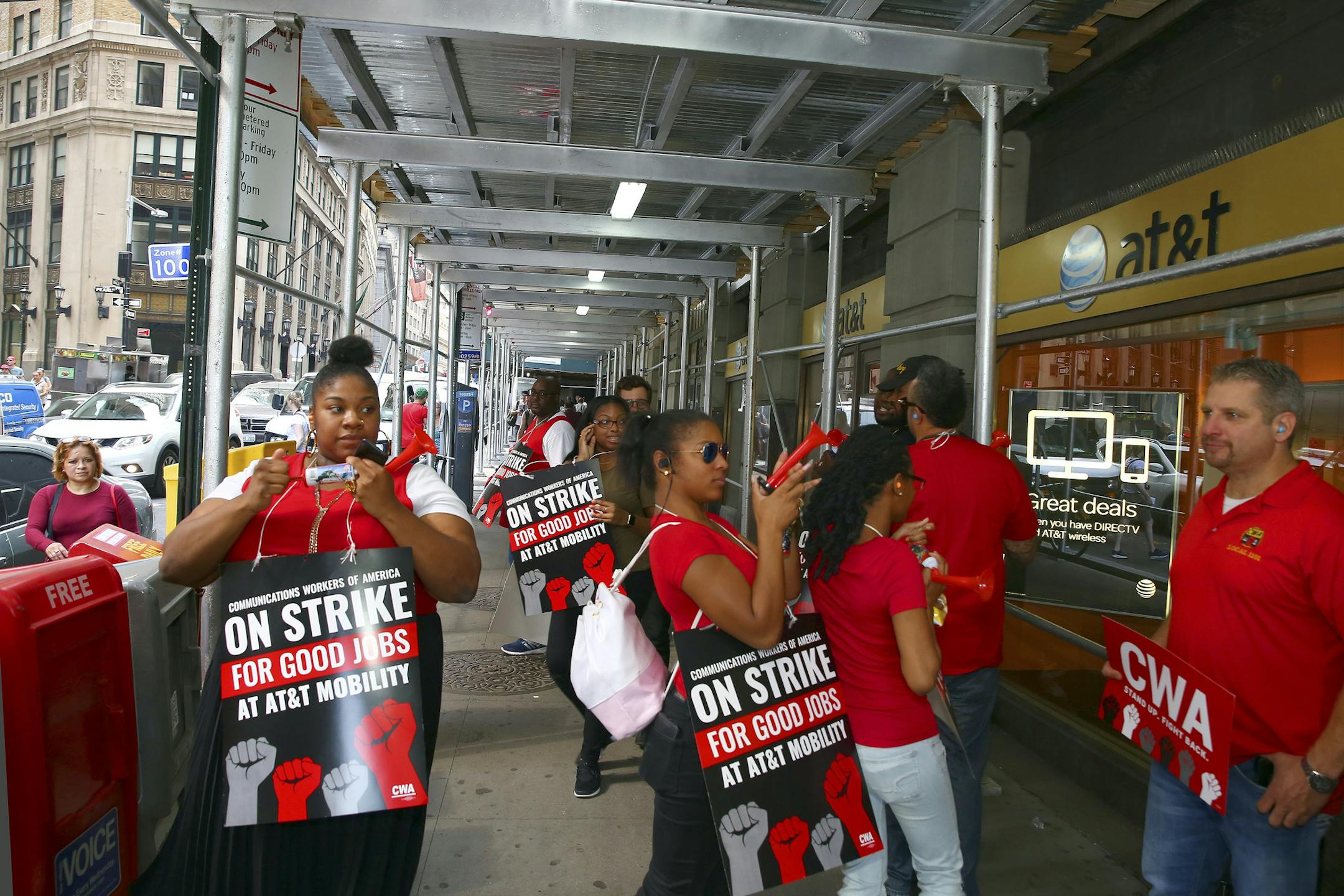 AT&T employees picket outside a store on Wall Street in New York on Friday. (Andrea Mohin/The New York Times)