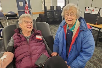 Barbara Swartwoudt sits in a chair donating blood while Cindy Anderson accompanies her.