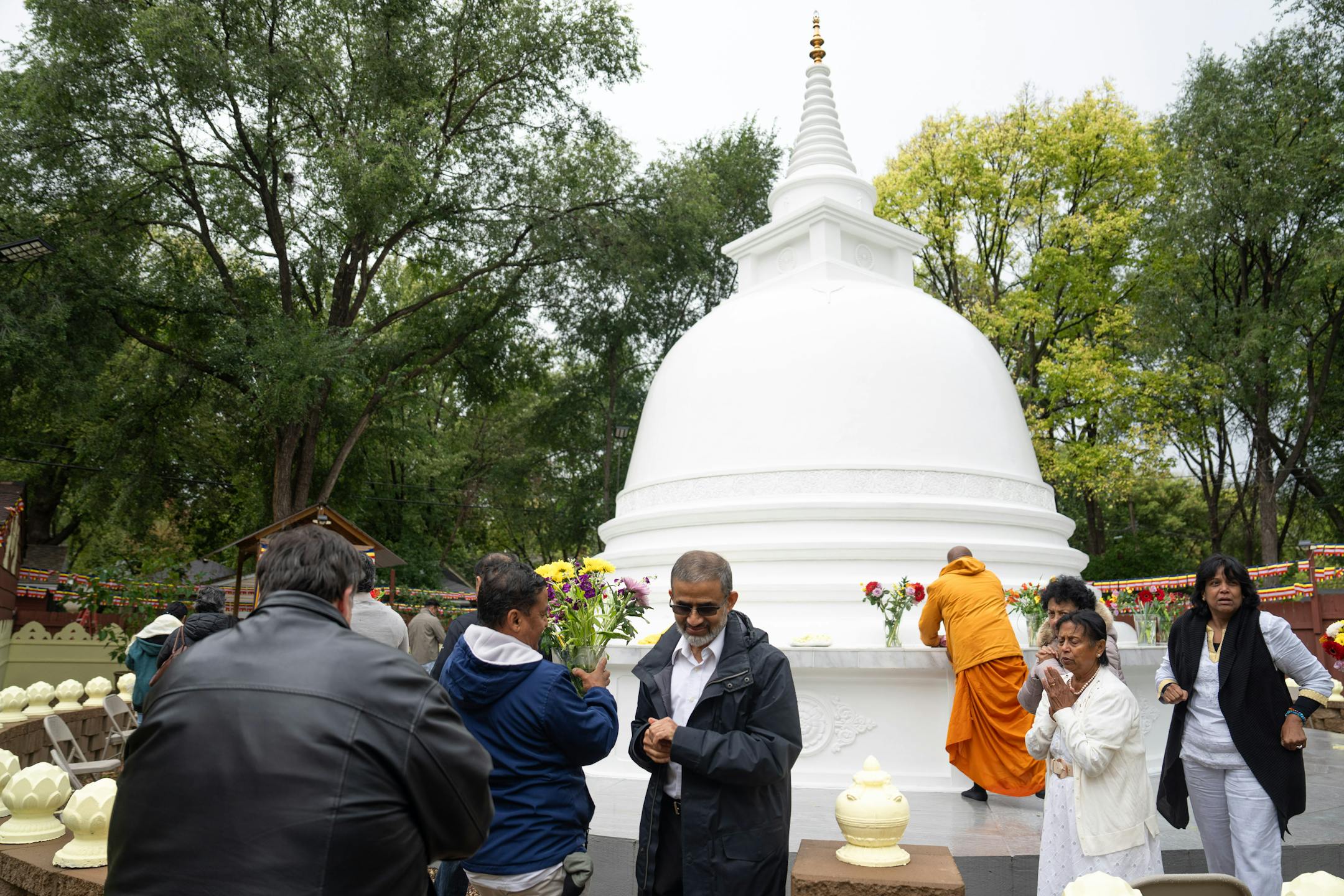 Attendees brought flowers to be placed on the Stupa Friday, Oct. 6, 2023 Minneapolis, Minn. This Stupa Unveiling marks a significant milestone in the history of Minnesota Buddhist Vihara and is an occasion of great joy and appreciation. A Stupa is a large white cement dome topped with a brass pinnacle. A sacred stupa is a physical structure in which a relic of the Buddha, enlightened beings, or holy books is enshrined. It creates an opportunity for people to circumambulate and cultivate positive vibration and spiritual development. ] GLEN STUBBE • glen.stubbe@startribune.com