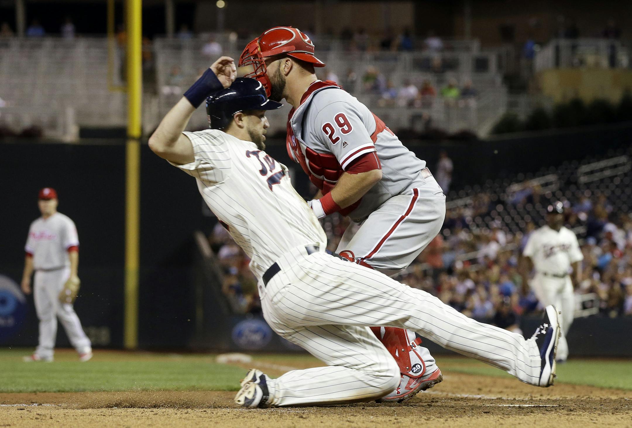 Minnesota Twins' Trevor Plouffe slides past Philadelphia Phillies catcher Cameron Rupp to score on a sacrifice fly by Max Kepler during the seventh inning of a baseball game Wednesday, June 22, 2016, in Minneapolis. The Twins won 6-5. (AP Photo/Jim Mone)