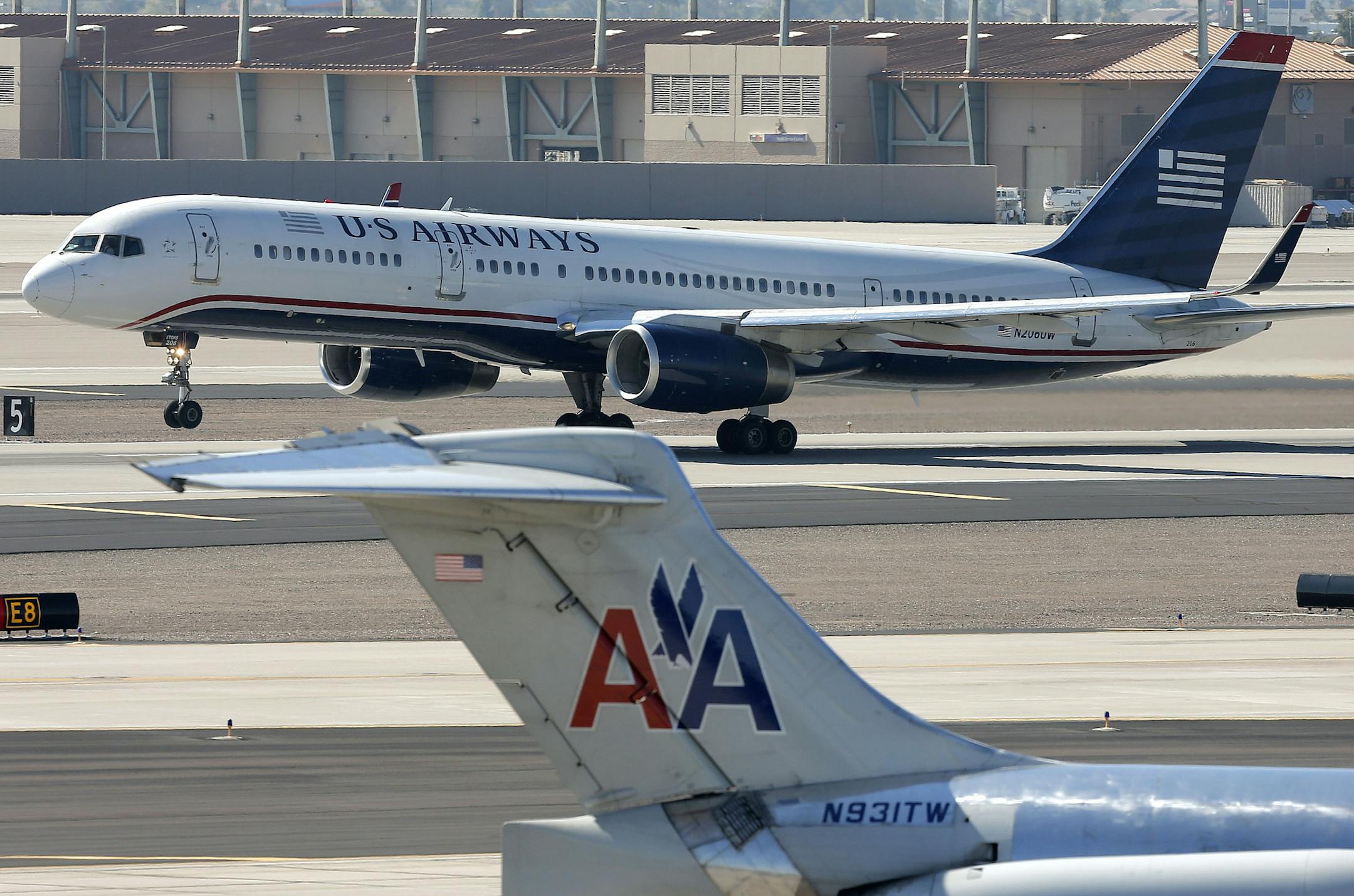 FILE - In this Thursday, Feb. 14, 2013, file photo, a U.S. Airways jet passes an American Airlines jet at Sky Harbor International Airport in Phoenix. The merger of the two airlines has given birth to a mega airline with more passengers than any other in the world. The Justice Department and a number of state attorneys general on Tuesday, Aug. 13, 2013, challenged a proposed $11 billion merger between US Airways Group Inc. and American Airlines' parent company, AMR Corp. (AP Photo/Matt York, fil