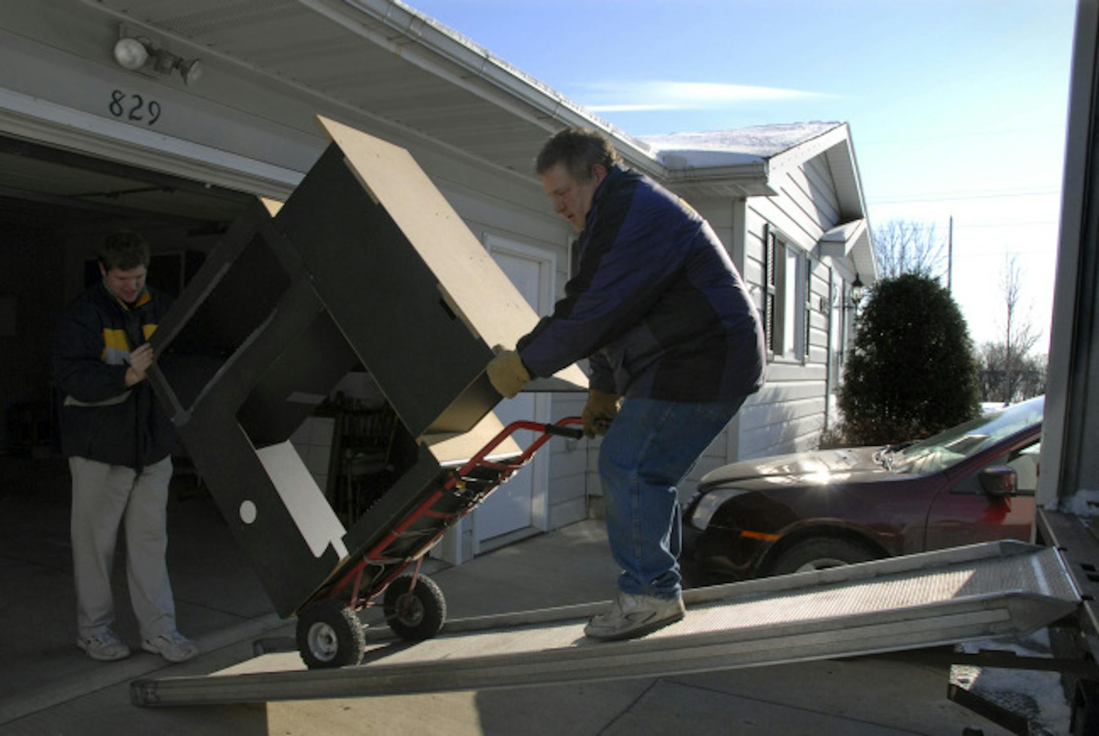 Mike Martin, left, and his dad, John Martin, moved an entertainment unit into John and Sheryl Martin's new home — the first house they have ever bought. They worked nearly five years to pay off credit cards.