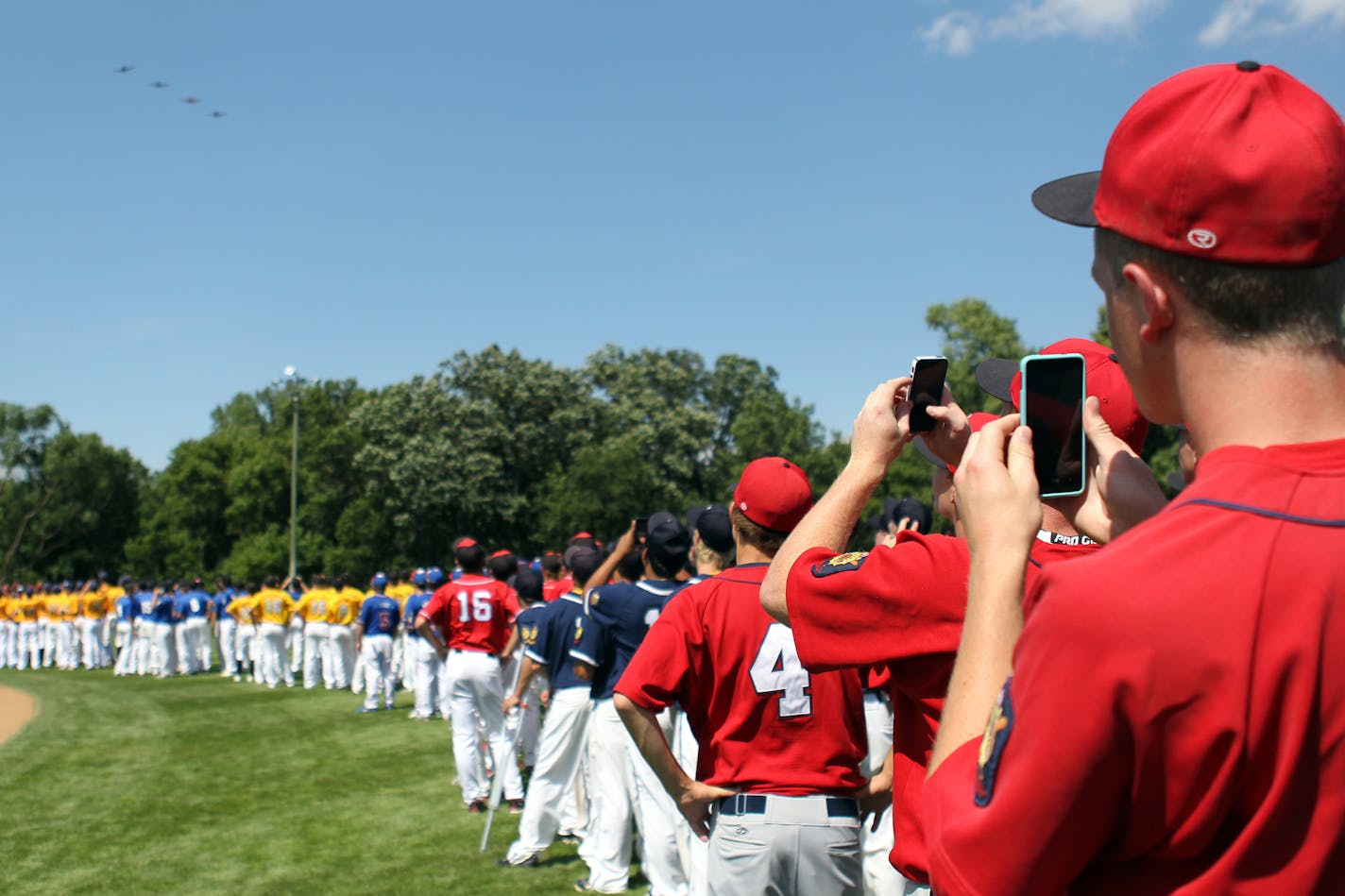 Rochester Patriots players and other teams watch and take photos on their phones of the military jet flyover for the Minnesota American Legion State Baseball Tournament at the Braemar Field complex in Edina, Minn., on Thursday, August 1, 2013. ] (ANNA REED/STAR TRIBUNE) anna.reed@startribune.com (cq) ORG XMIT: MIN1308011545295488