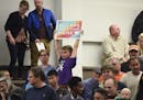 A child holds a sign during a city council meeting on refugee resettlement moratoriums Monday, Oct. 23, 2017, at city council chambers in St. Cloud, M