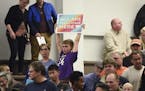 A child holds a sign during a city council meeting on refugee resettlement moratoriums Monday, Oct. 23, 2017, at city council chambers in St. Cloud, M