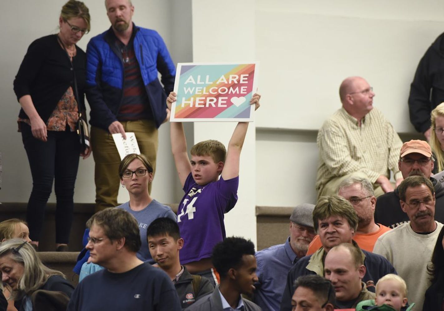 A child holds a sign during a city council meeting on refugee resettlement moratoriums Monday, Oct. 23, 2017, at city council chambers in St. Cloud, Minn.